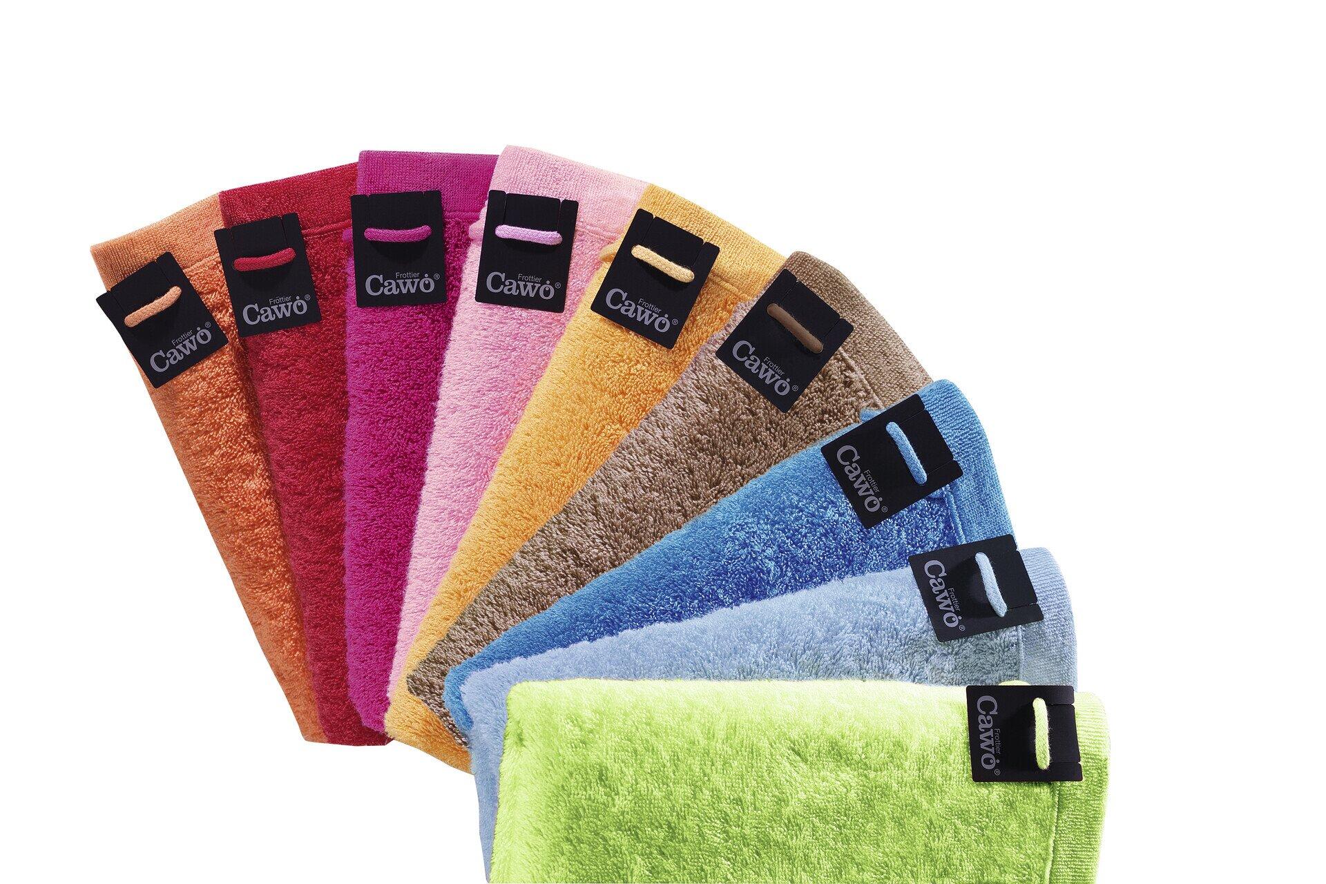 Sechs farbenfrohe Cawö Baumwollwaschlappen in Rot, Pink, Orange, Gelbgrün, Blau und Grün, ansprechend drapiert und mit dem Cawö-Logo versehen.