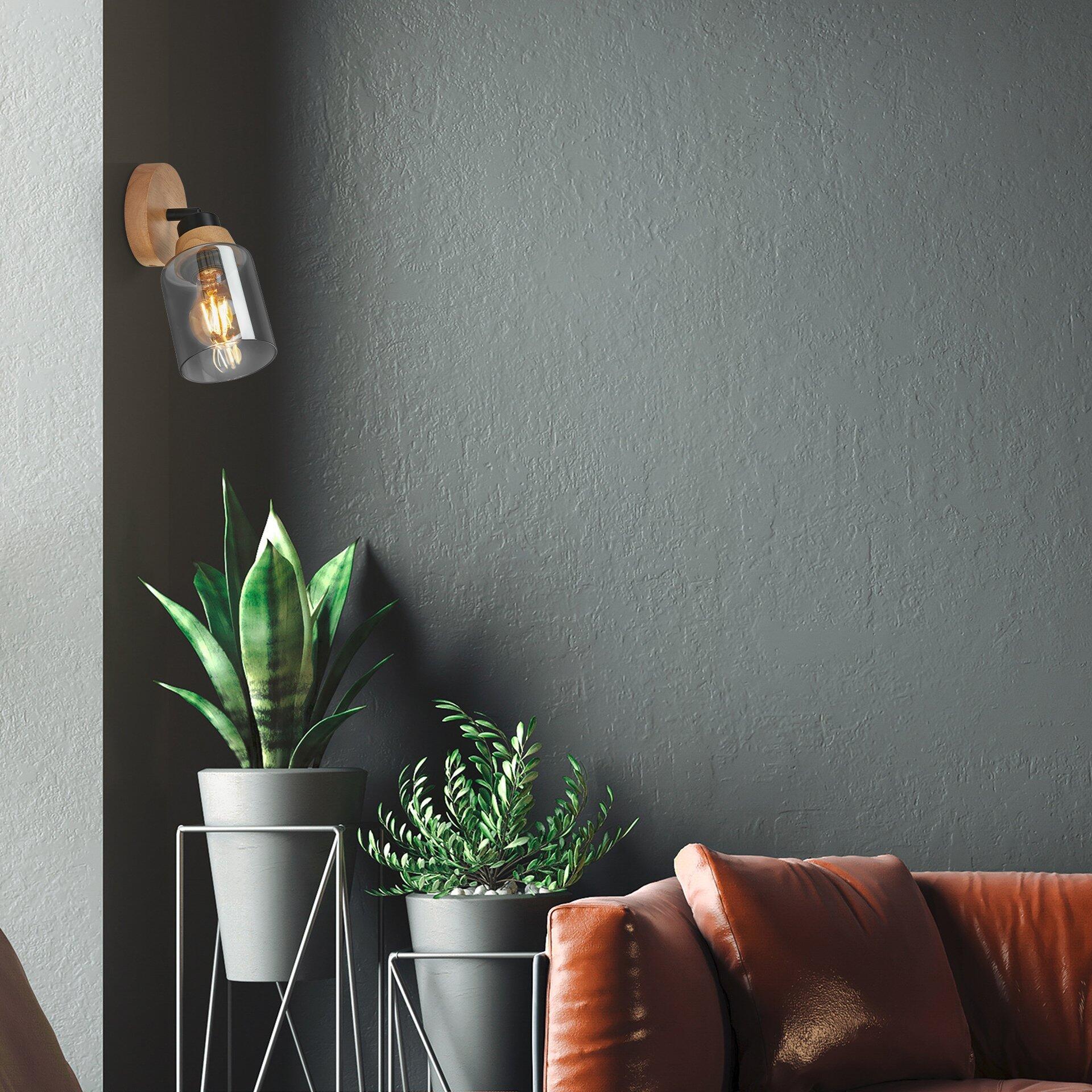 Wandleuchte Spot von Hema mit dunkelbrauner Metallhalterung, Holzapplik und Glaskolben, befestigt an einer grauen Wand.