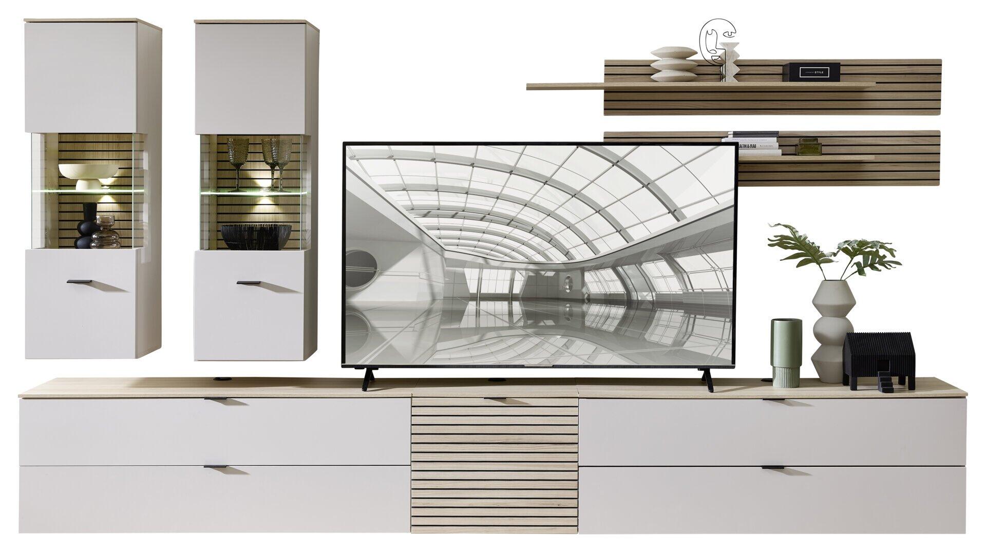 Moderne TV-Konsole Ina mit Riva Eiche Nachbildung und weißen MDF-Fronten, inklusive Schubladen, geschlossenen Fächern und LED-Beleuchtung, dargestellt in einer stilisierten Wohnumgebung mit passenden Sideboards und Wandablage.