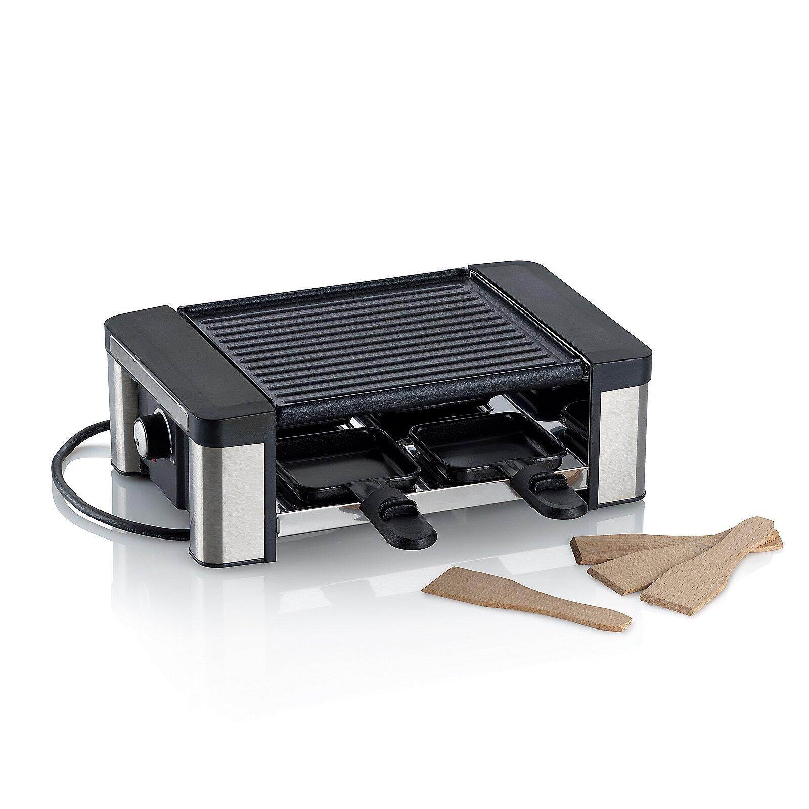 Raclette/Grillplatte Timur mit silbernem Korpus, schwarzer Grillfläche und zwei Käsepfännchen, aus nah unten liegender Perspektive fotografiert.