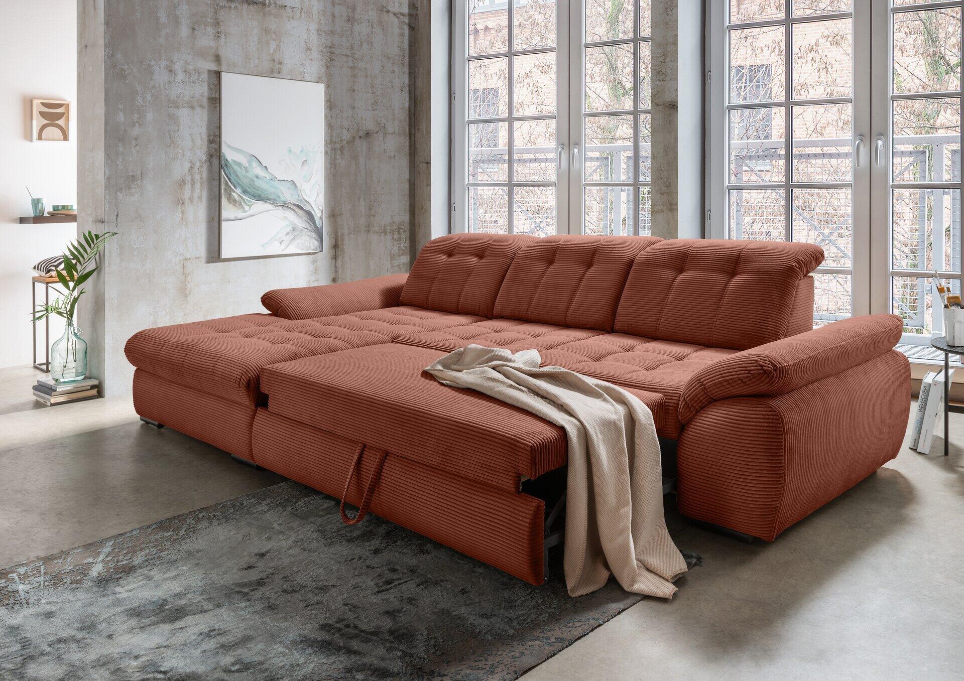 Ecksofa Rigatti im geöffneten Zustand mit ausgezogener Schlaffunktion und Sitztiefenverstellung vor einer Betonwand mit Gartenblick.