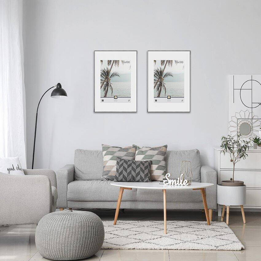 Bilderrahmen Kyoto: Zwei Rahmen mit Palmenmotiven über einem grauen Sofa in einer skandinavischen Wohnszene.