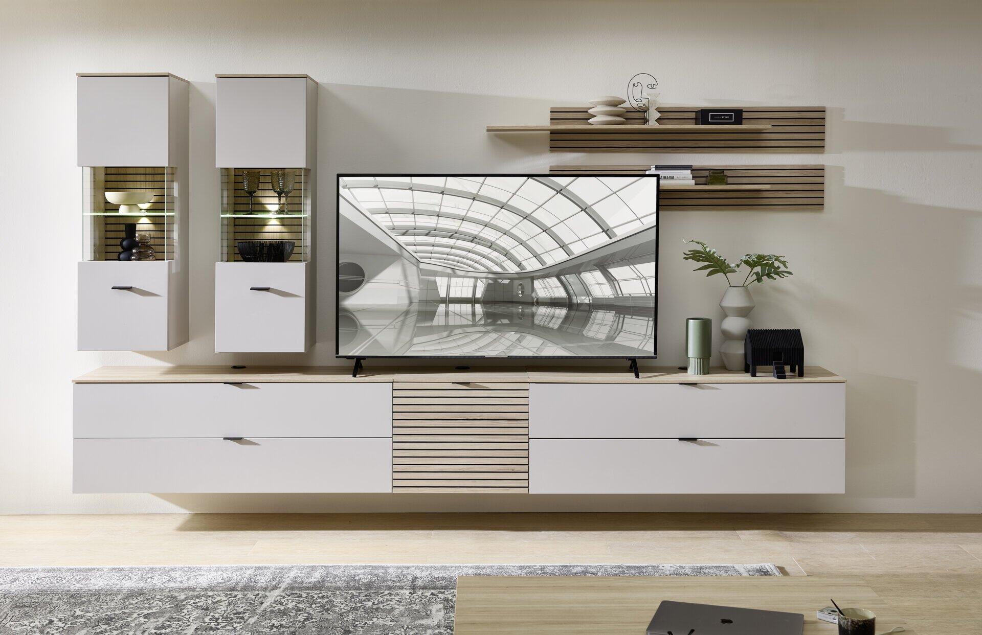 Moderne TV-/Wohnlösung Ina mit Vitrine, TV-Schrank und dekorativen Wandelementen, präsentiert in einer Frontalperspektive mit LED-Beleuchtung und schlichtem Design.
