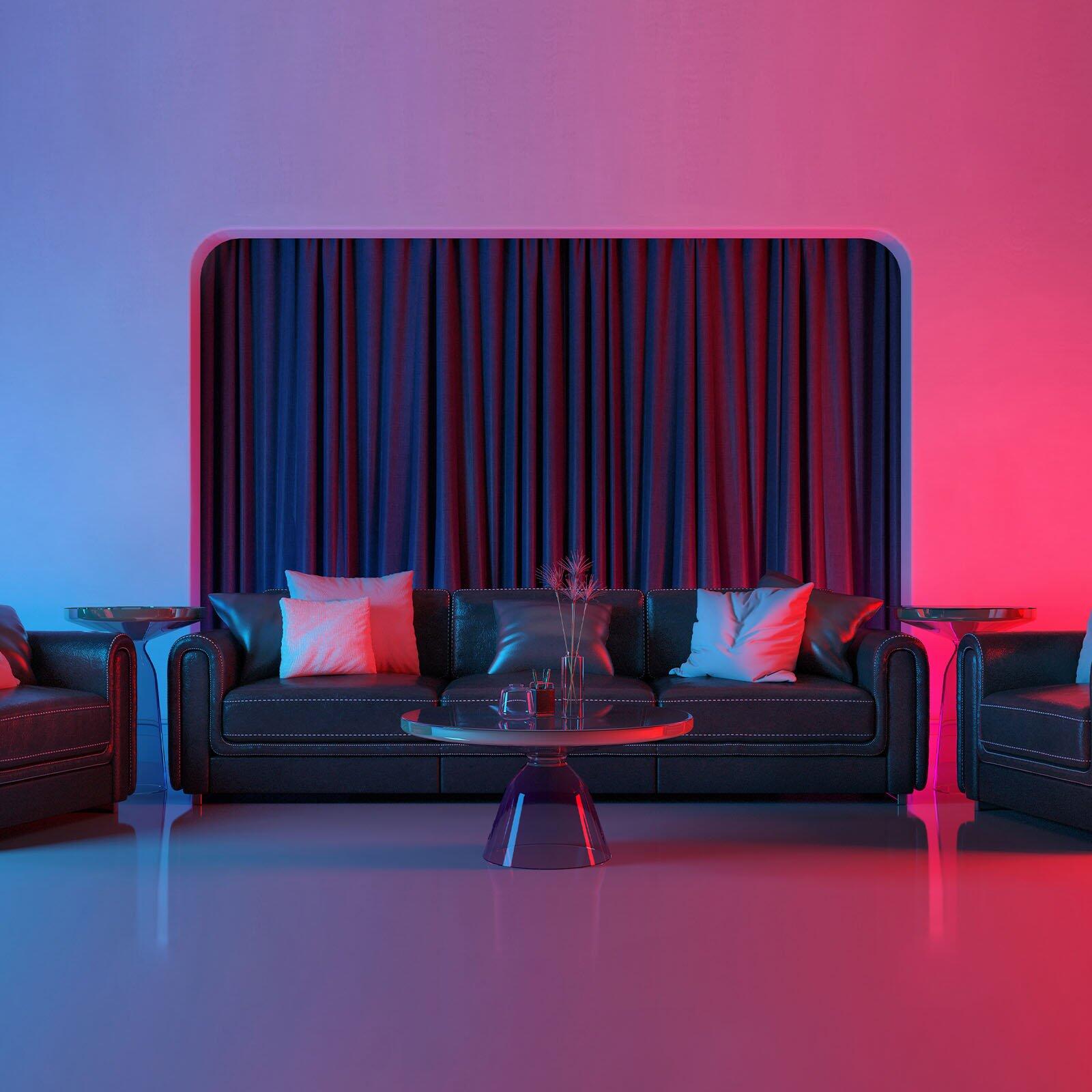 LED-Band "Flow" beleuchtet ein schwarzes Ledersofa mit roten und blauen Farbtönen, wobei die Frontalperspektive das Design und die Anordnung von Sofa, Sesseln und Couchtisch betont.