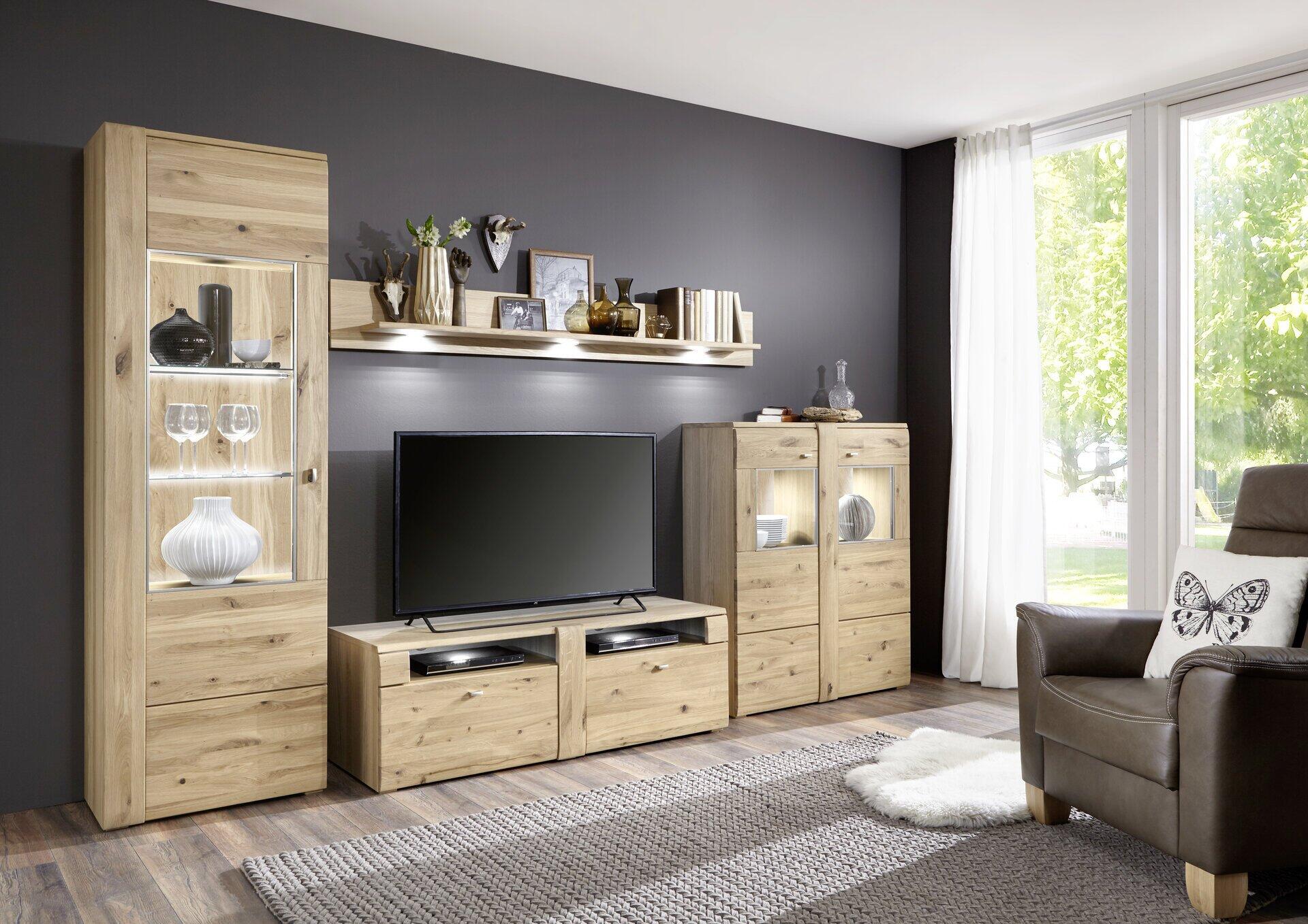 Moderne TV-/Wohnlösung Colorado mit Sideboards, TV-Lowboard und Hängeregal in altereiche geölter Ausführung, dargestellt in einer seitlichen Perspektive vor einem Wohnzimmer mit großzügiger Fensterfront.