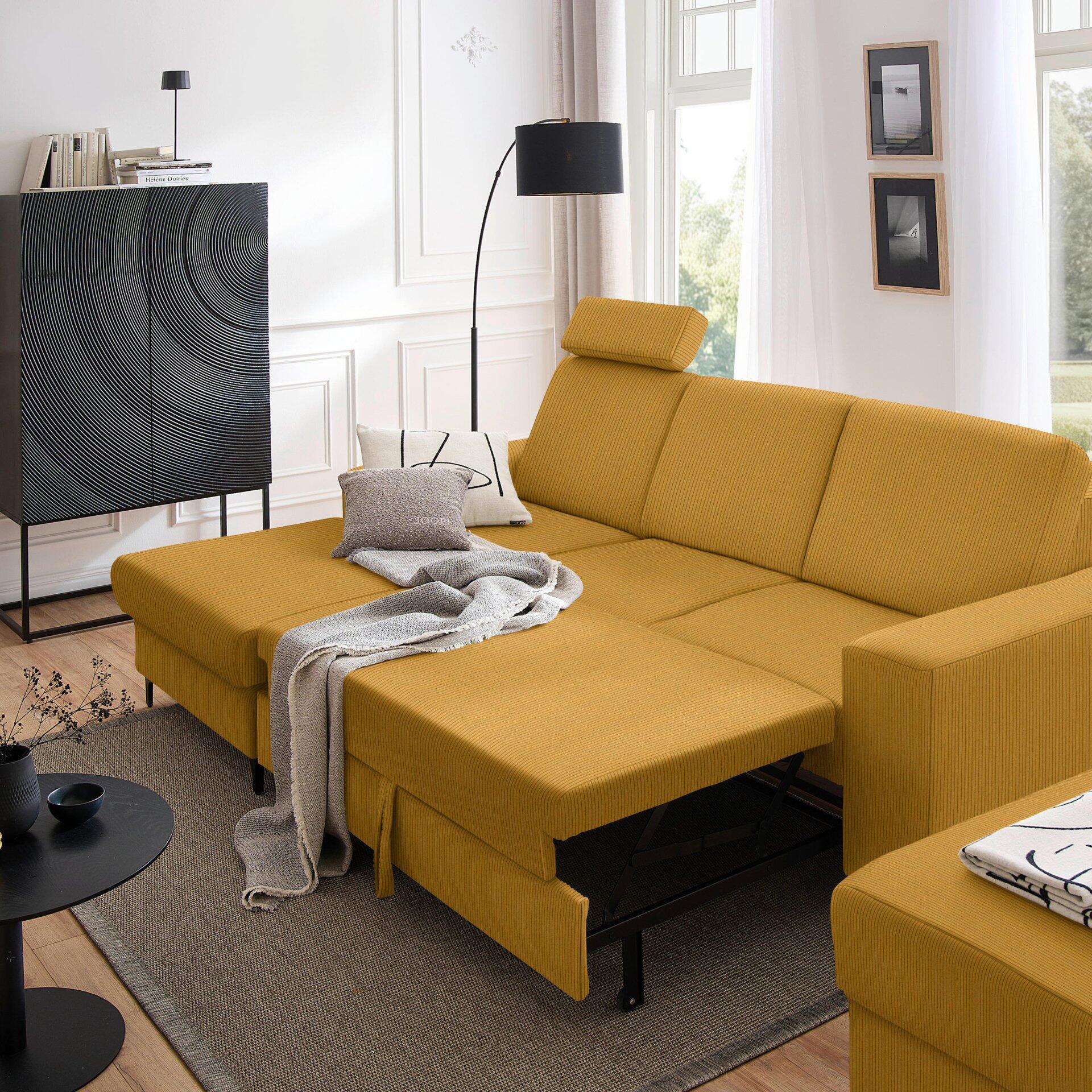 Gelbes Ecksofa Balina in L-Form mit ausgezogenen Schlafbereich und Winkelfüßen, präsentiert in einer modernen Wohnzimmerumgebung.