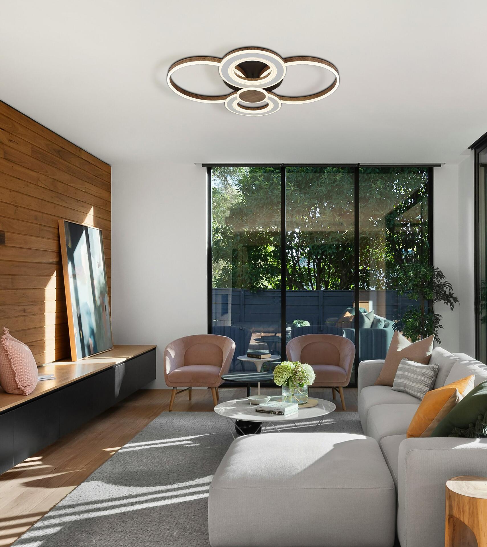 Moderne Deckenleuchte MARA mit ringförmigen Elementen erhellt das Wohnzimmer aus Augenhöhe.
