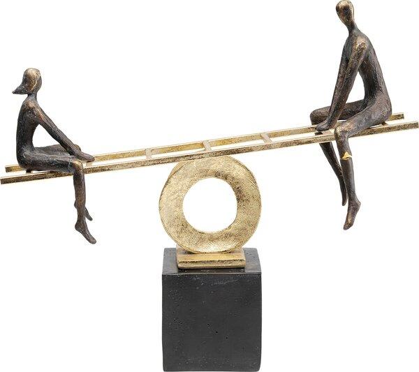 Deko Figur Balance: Goldfarbene Skulptur mit schwarzem Sockel und einer Waage, auf der bronzefarbene stilisierte Figuren sitzen.