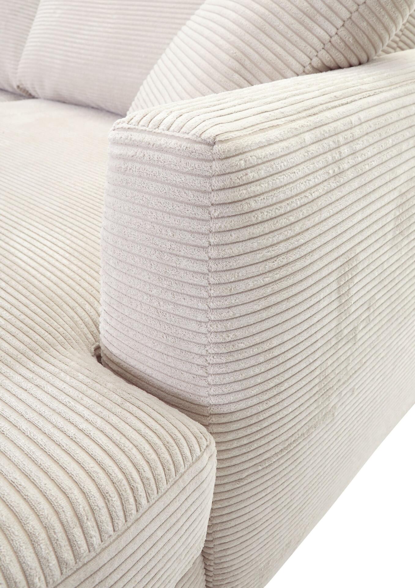 Detailaufnahme des Armteils und der abgerundeten Rückenlehne des Sofas, zeigt die cremefarbene Cordstoff-Textur mit vertikalen Streifen.