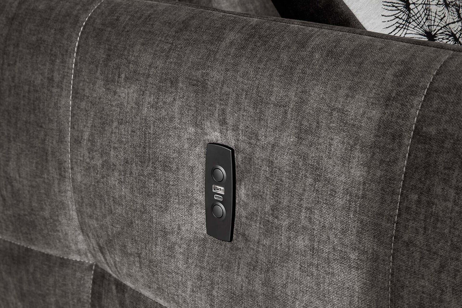 Detailaufnahme der dunkelgrau bezogenen Armlehne der Wohnlandschaft Zoom mit Bedienelement für elektrische Funktionen wie Kopfstützen- und Rückenlehmenverstellung.