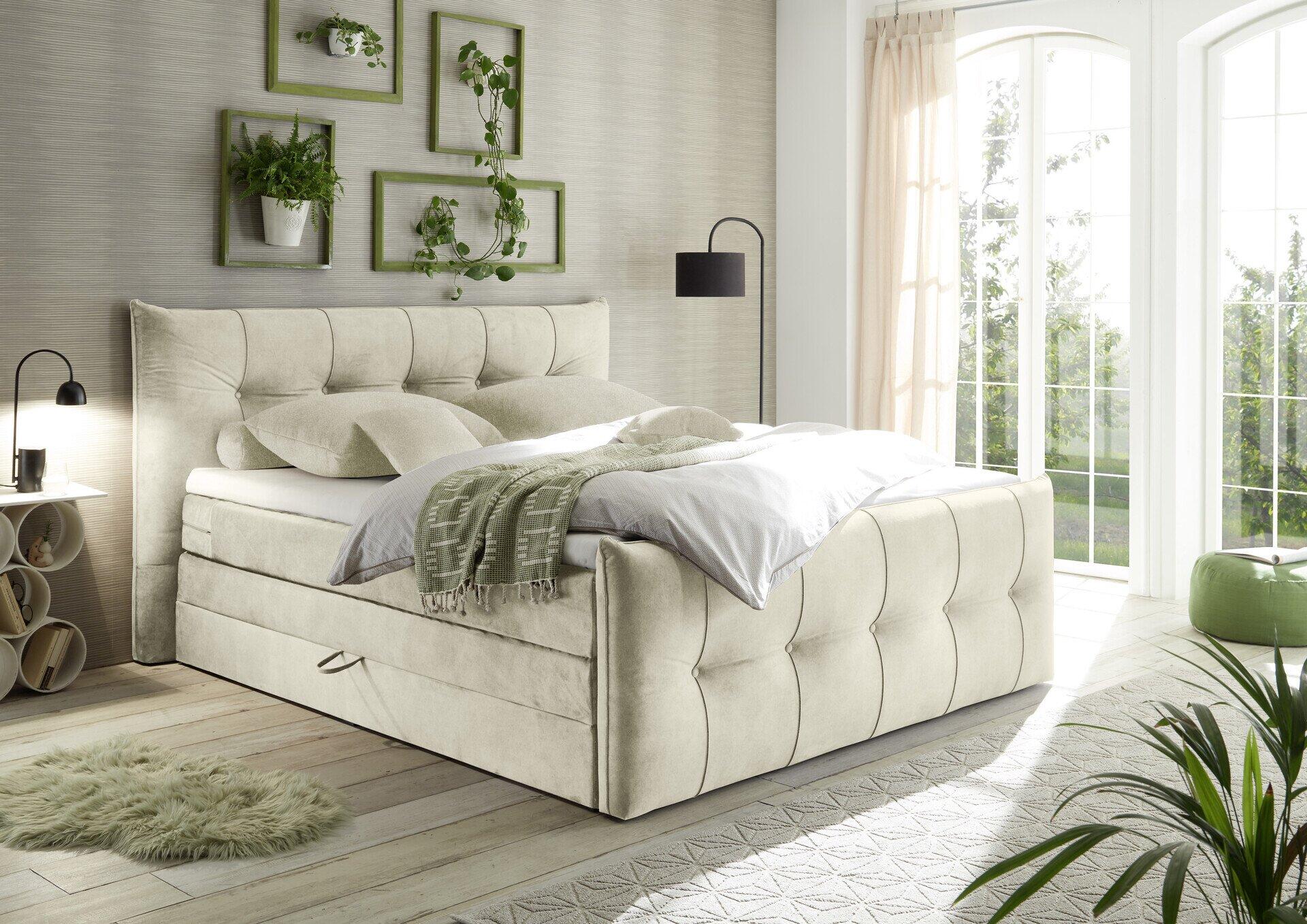 Boxspringbett Maracana 6 mit hohem, gepolsterten Kopfteil und integriertem Bettkasten, dargestellt aus einer leicht schrägen Perspektive in einem hellen Schlafzimmer.