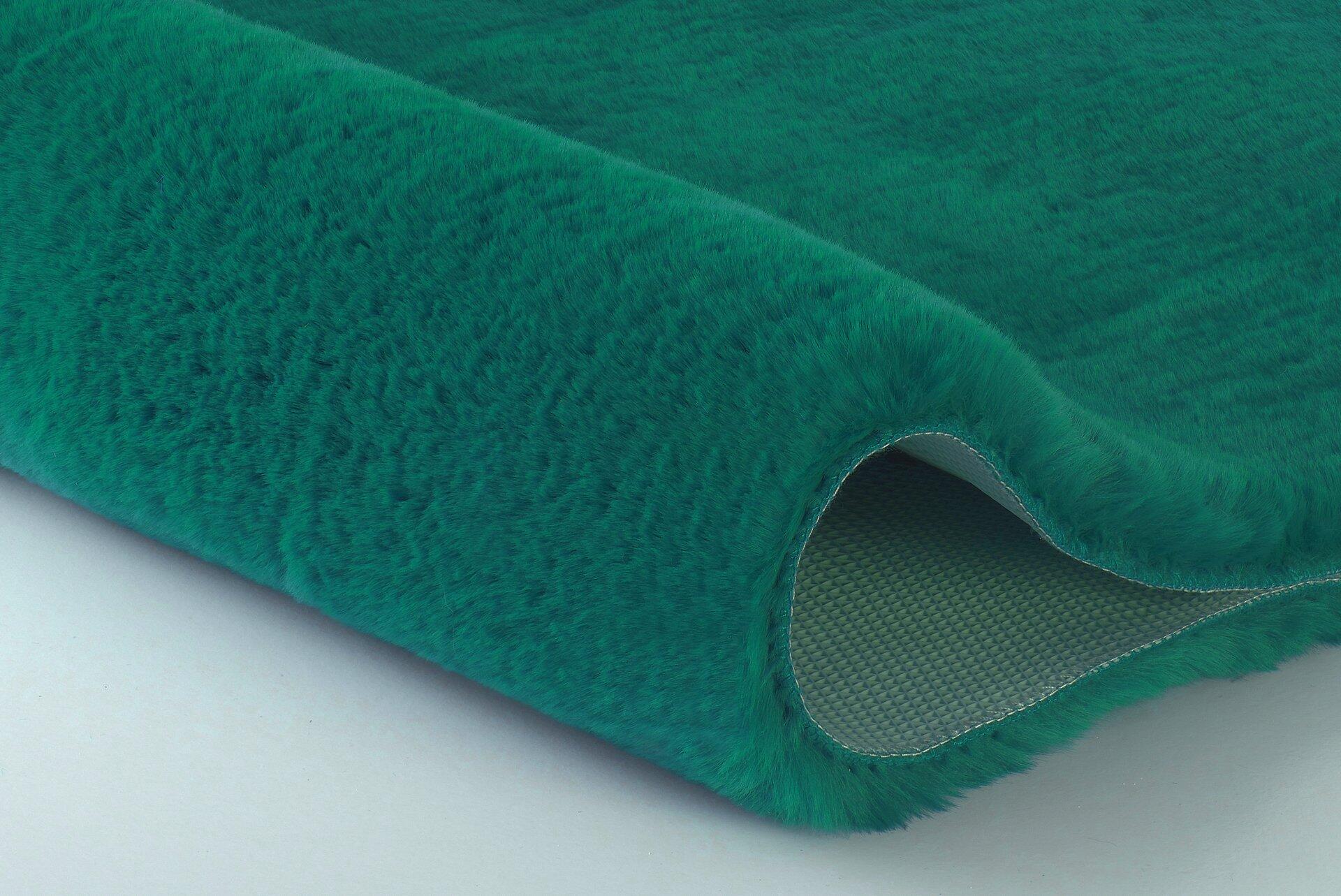 Flauschiger petrolfarbener Badteppich Cony aus Polyester, aus der Vogelperspektive leicht angewinkelt und gefaltet, um die Unterseite aus grauem Stoff zu zeigen.