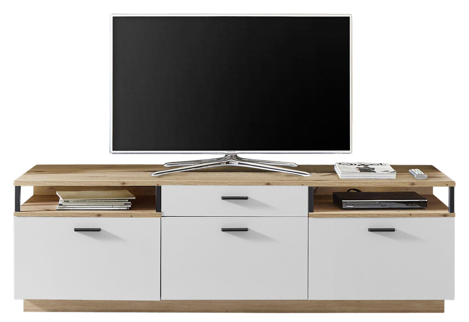 Lowboard Basset in Eiche Artisan Melamin mit drei Holztüren, einem Schubkasten und zwei Fächern, gezeigt in Frontansicht mit Fernseher und Accessoires auf der Ablagefläche.