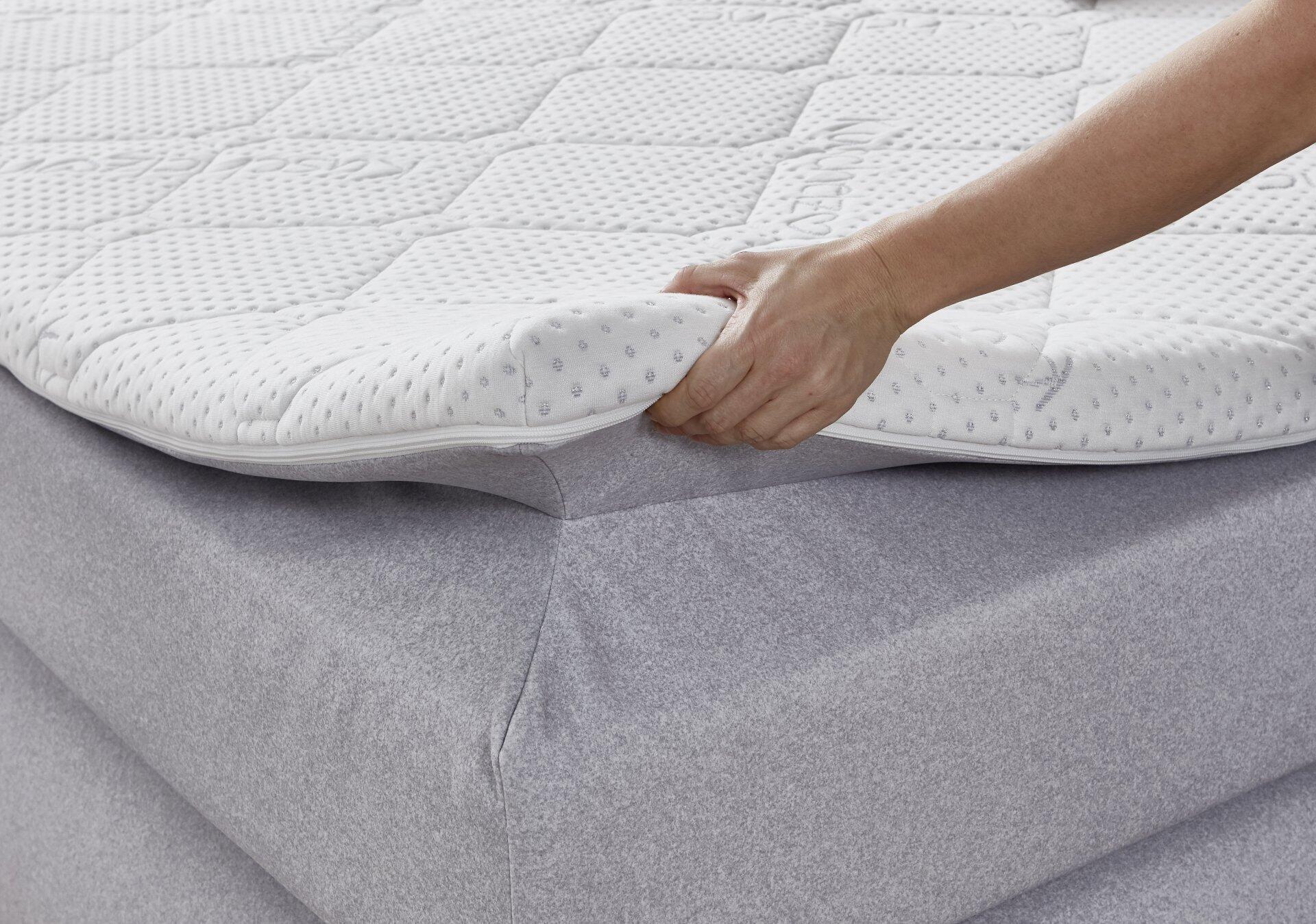 Detailaufnahme des Boxspringbettes Graz BX2630 mit Bonell-Federkern, die eine strukturierte Matratzenoberfläche und die Anhebefunktion zur Demonstration der Polsterung zeigt.