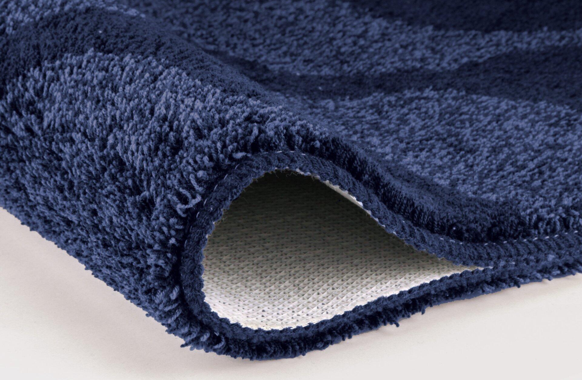 Detailaufnahme des navyblauen WC-Vorlegers Onda mit flauschigem Tiefflor auf der Oberseite und robuster, hellgrauer Filzunterseite.