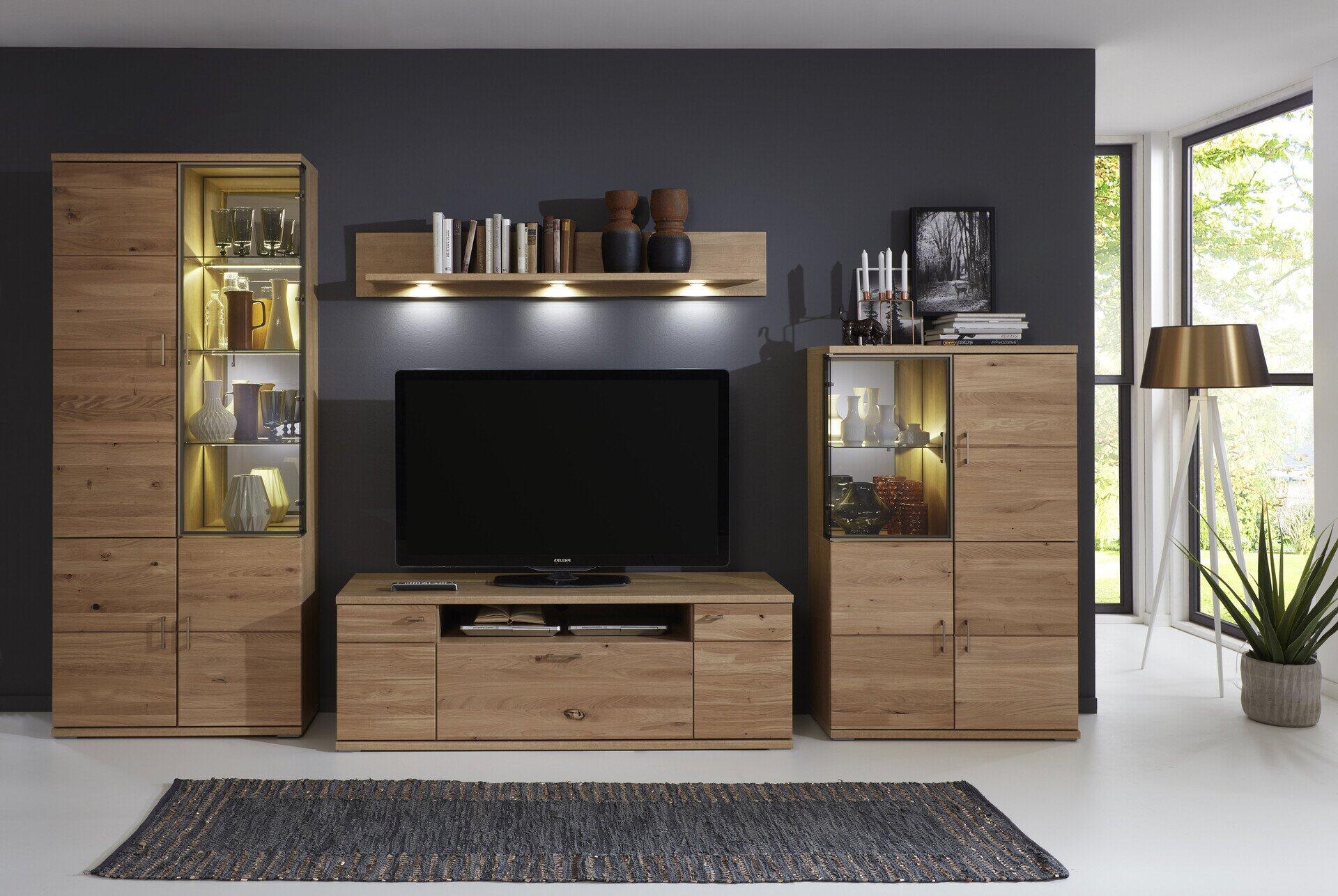 TV-Wohnlösung Brilon mit zwei Vitrinen, TV-Schrank mit Schubladen und Türen sowie Wandboard, dargestellt in einer seitlichen Perspektive vor einer Wand mit Fenster und dekorativen Elementen.
