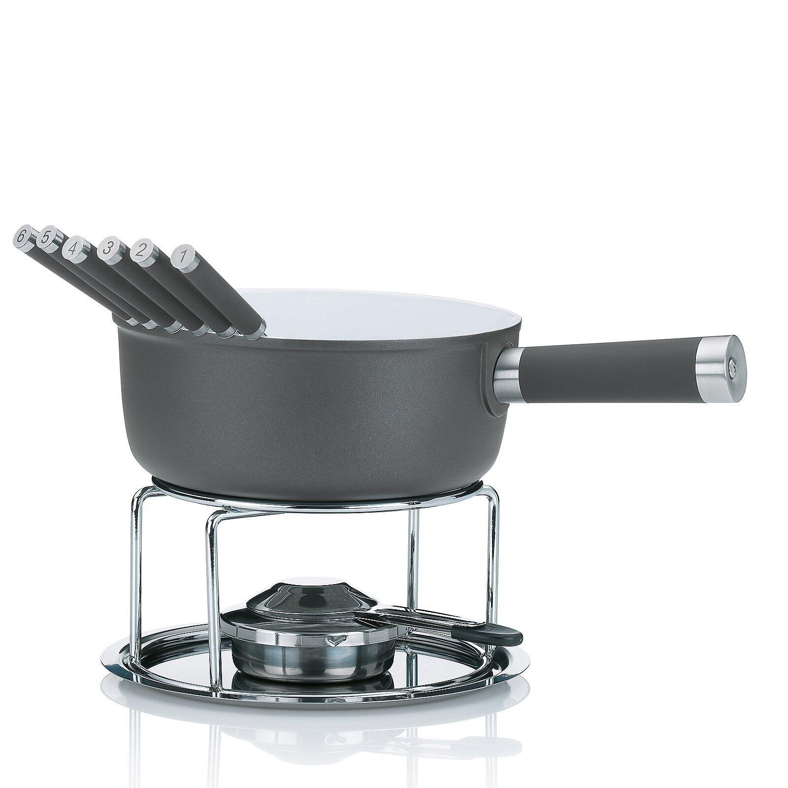 Käsefondue-Set Lancy mit Edelstahl-Topf, grauem Innenleben und sechs Kochlöffeln auf silberfarbenem Untergestell vor einem Herd.