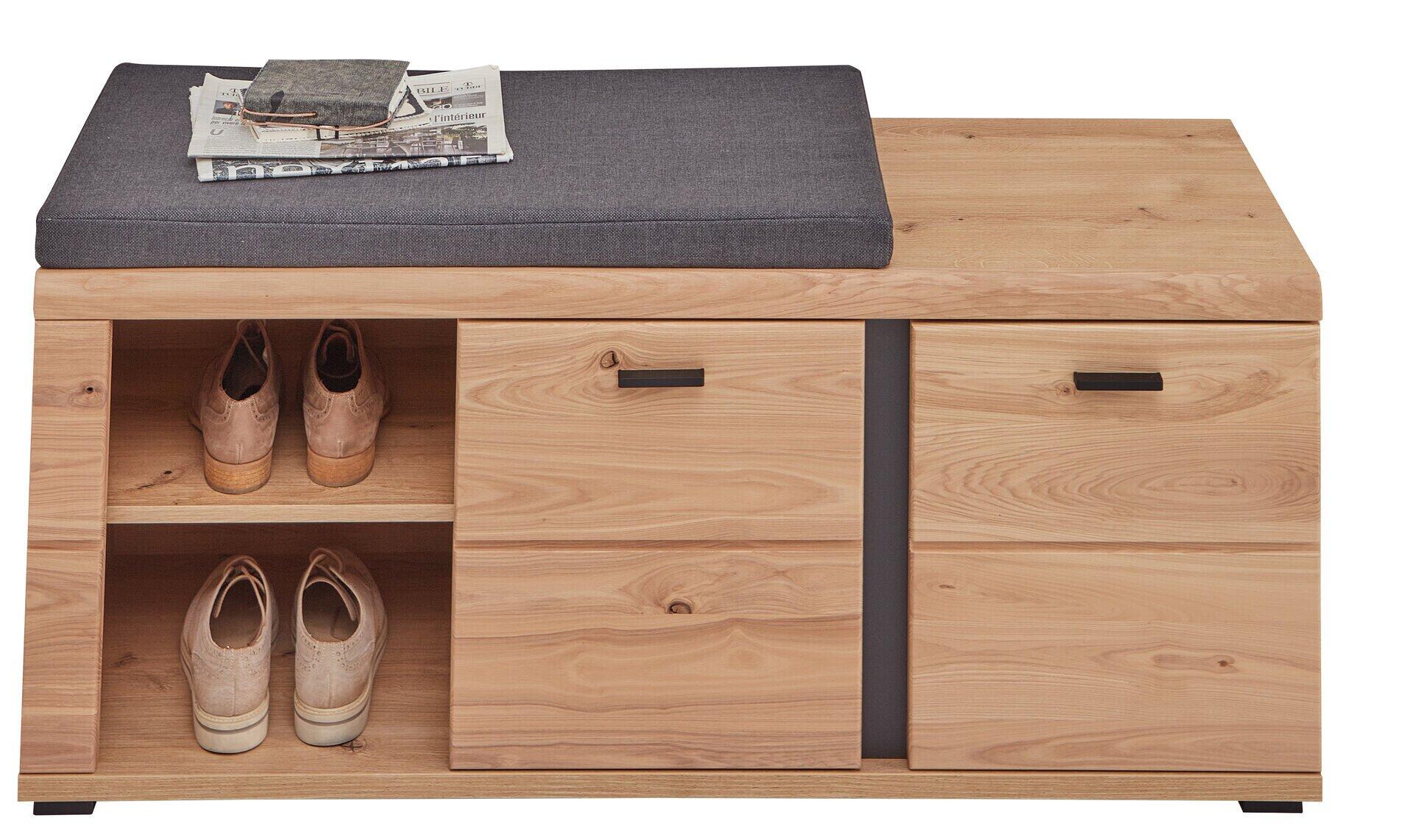 Bank, Sonos: Schuhschrank mit gebürsteter Holzfront, offene Schuhablagen mit Lederschuhen und Sitzfläche mit Anthrazit-Kissen.