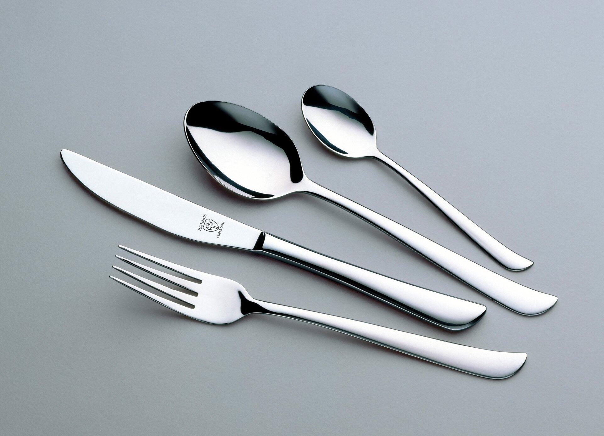 Menübesteck 30 tlg. Twist: Esslöffel, Gabel und Essmesser auf hellgrauem Hintergrund zeigen modernes Design und ergonomischen Griff mit Logo.