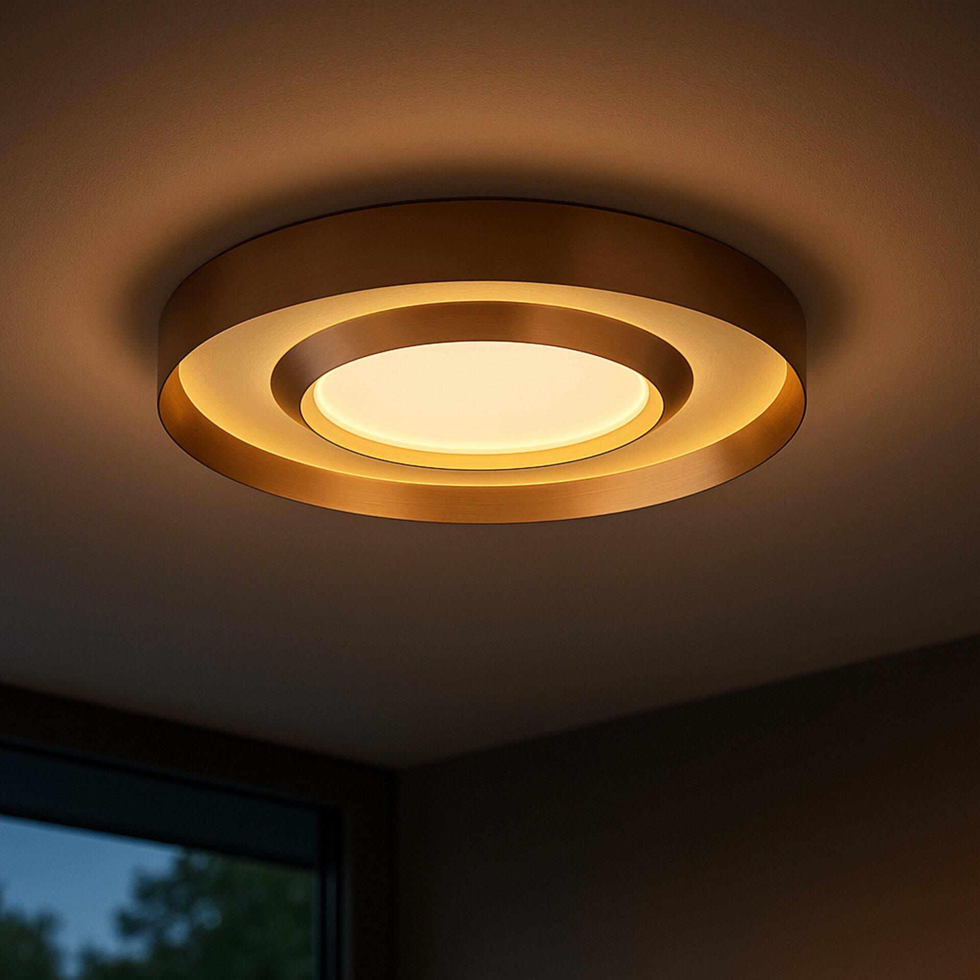 Deckenleuchte Onix mit zylindrischem, goldenen Ringdesign und gleichmäßig verteiltem, warmweißen Licht, dargestellt aus einer unteren Perspektive.