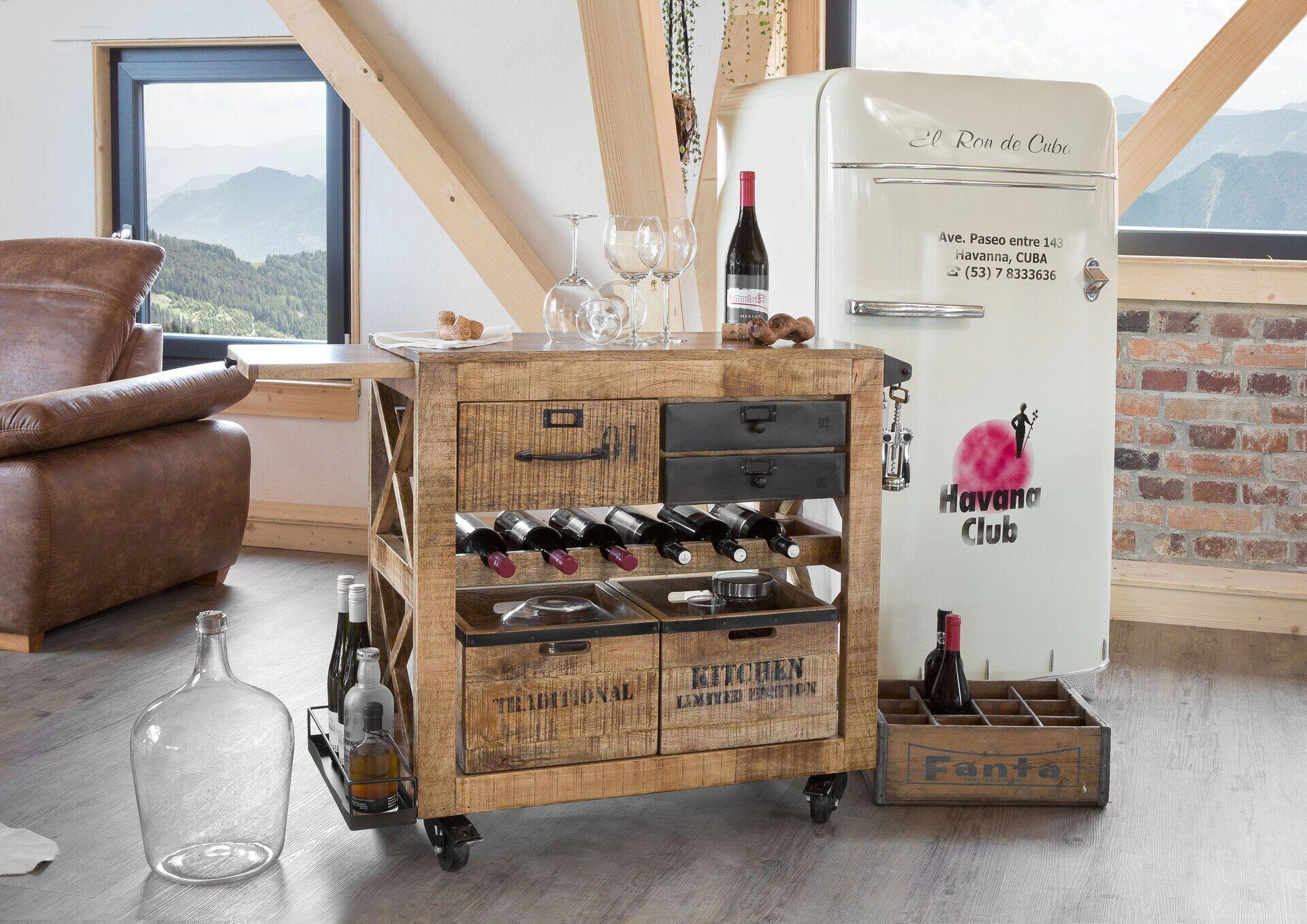 Servierwagen Warehouse mit Fächern und Halterungen für Weinflaschen und Gläser, präsentiert in einer stilvollen Wohnküche mit Vintage-Kühlschrank im Hintergrund.