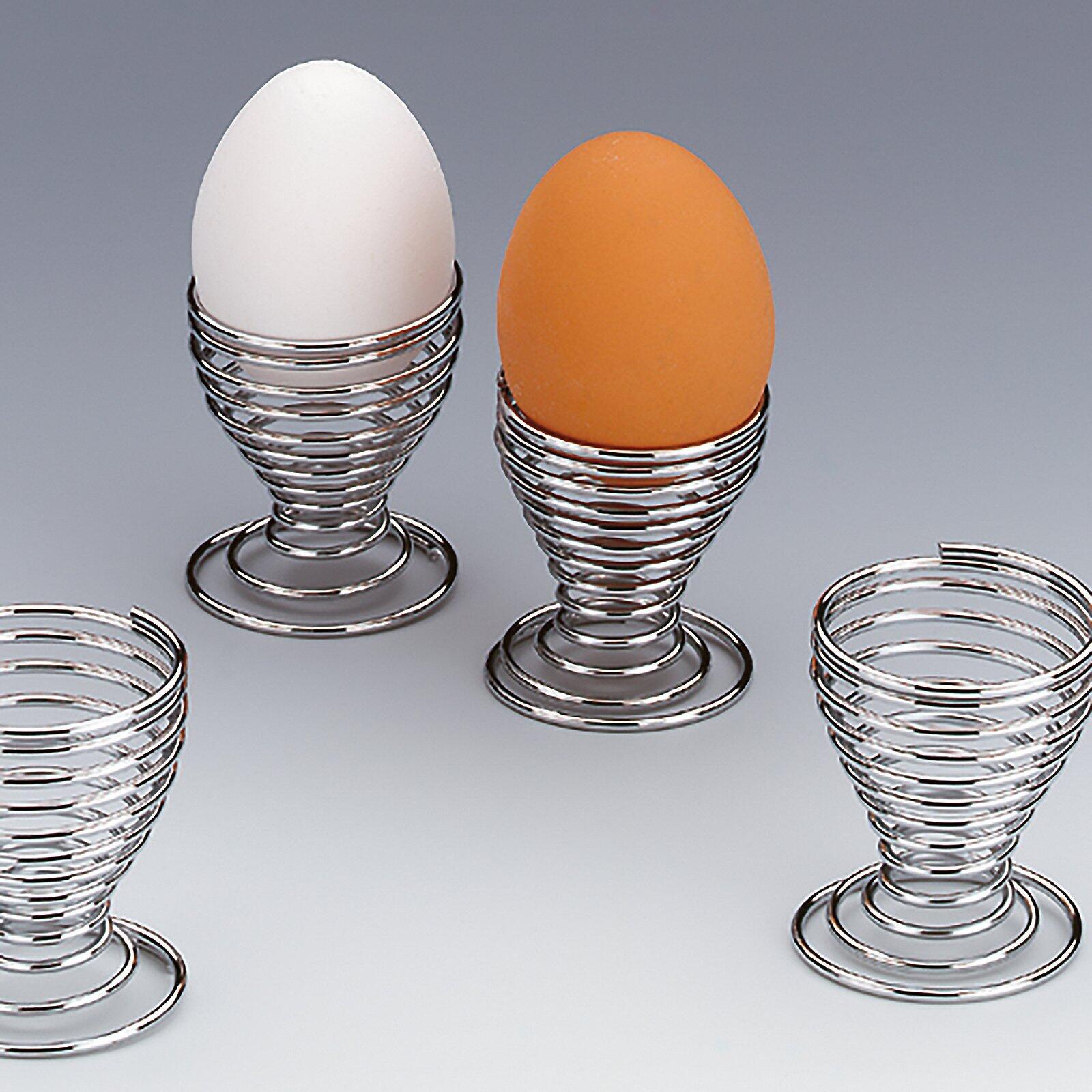 Drei Eierbecher Globul aus Chromstahl mit spiralförmigem Design, wobei ein weißes und zwei braune Eier sicher in den unterschiedlich großen Bechern platziert sind.