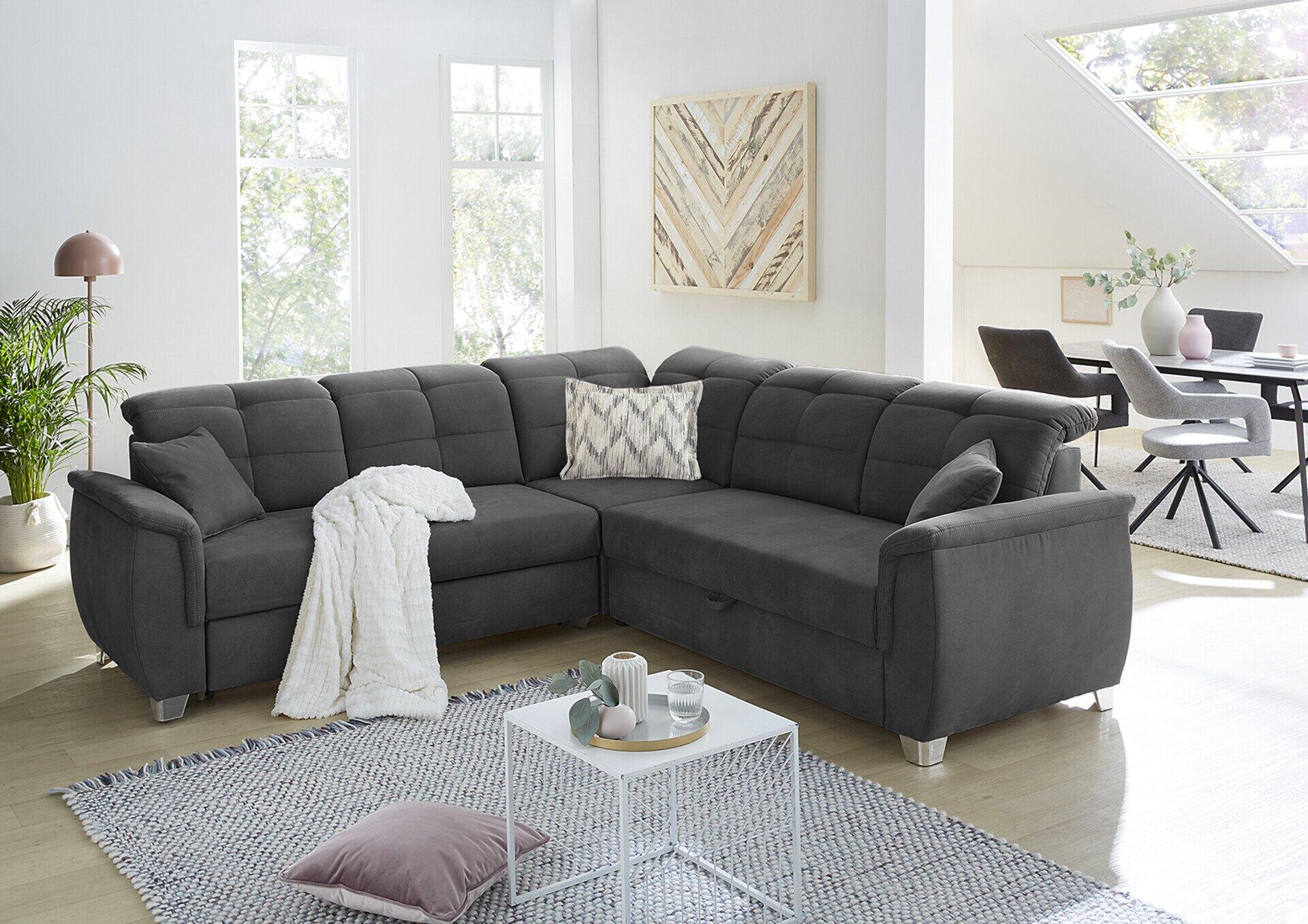 Wohnlandschaft Udine mit dunkelgrauem Microfaser-Korpus und grau gemusterten Kissen, ausgestattet mit Relaxfunktion und verstellbaren Kopfstützen, aus erhöhter Frontalperspektive im hellen Wohnzimmer.