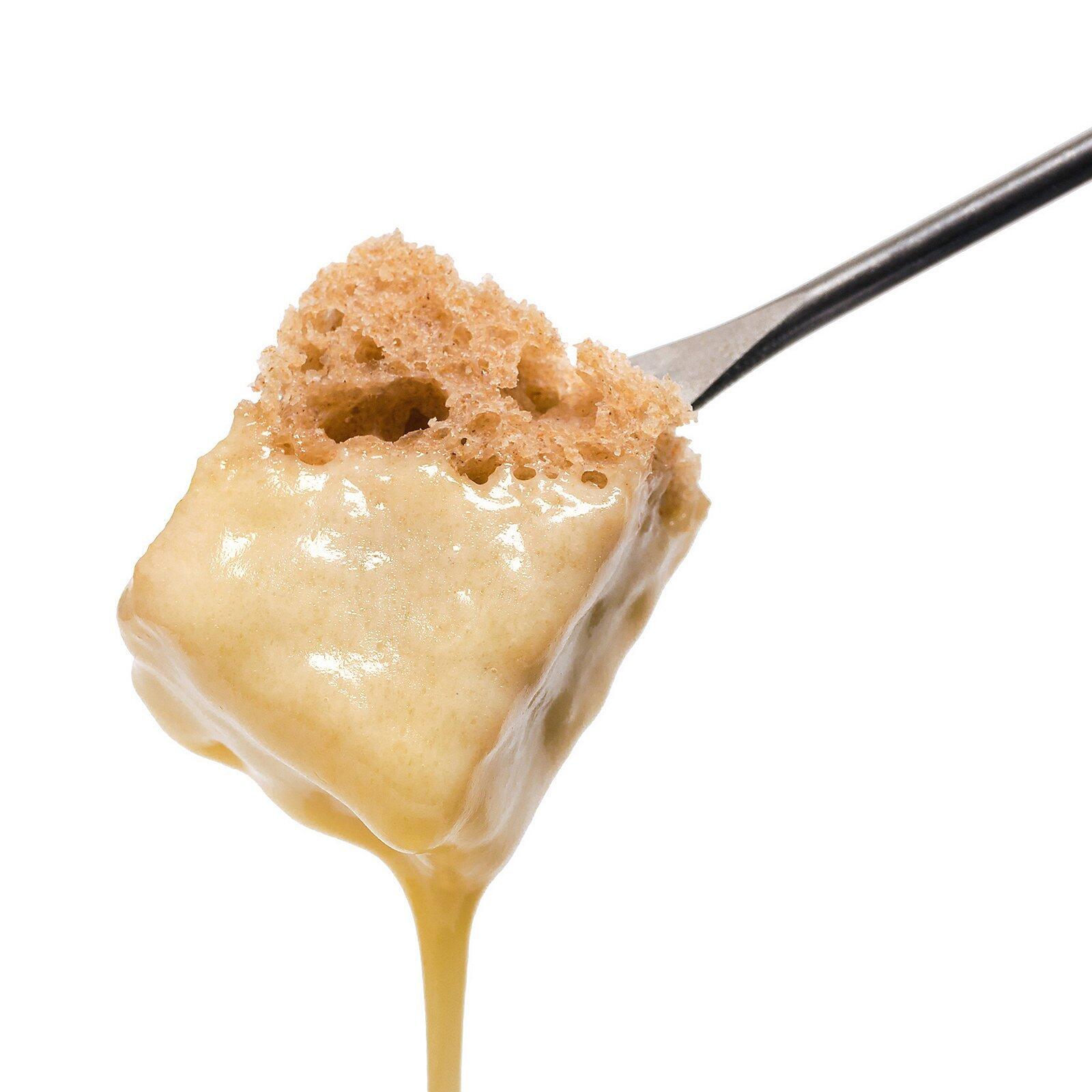 Morena Käsefonduegabel – silberne Gabel hält ein mit heller Glasur überzogenes Kuchenstück in Nahaufnahme.