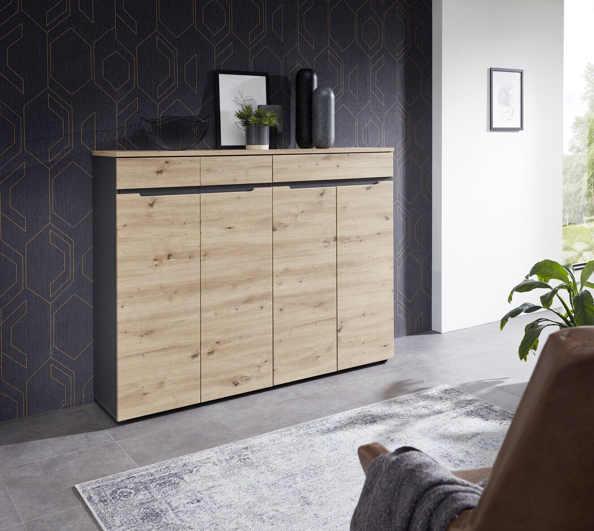 Schuhschrank Detroit mit vier Holztüren, einem Schubkasten und Ablagefläche, präsentiert in einem modernen Raum mit grauer Basis und Artisan Eiche Dekor.