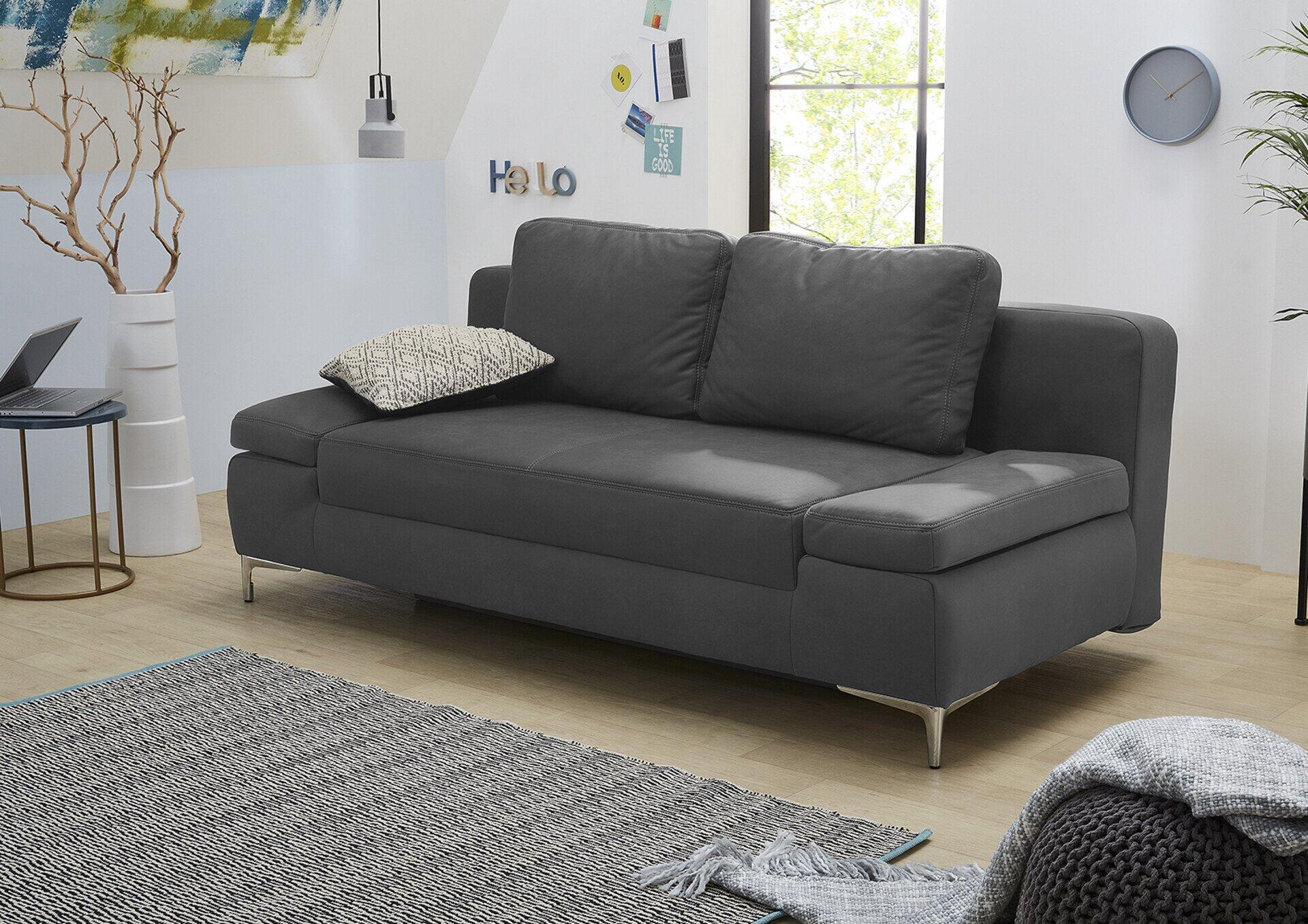 Schlafsofa Jano mit dunkelgrauem Microfaserbezug, chromfarbenen Füßen und abfallender Rückenlehne, in einer seitlichen Perspektive präsentiert, um die moderne Form und den Komfort zu betonen.
