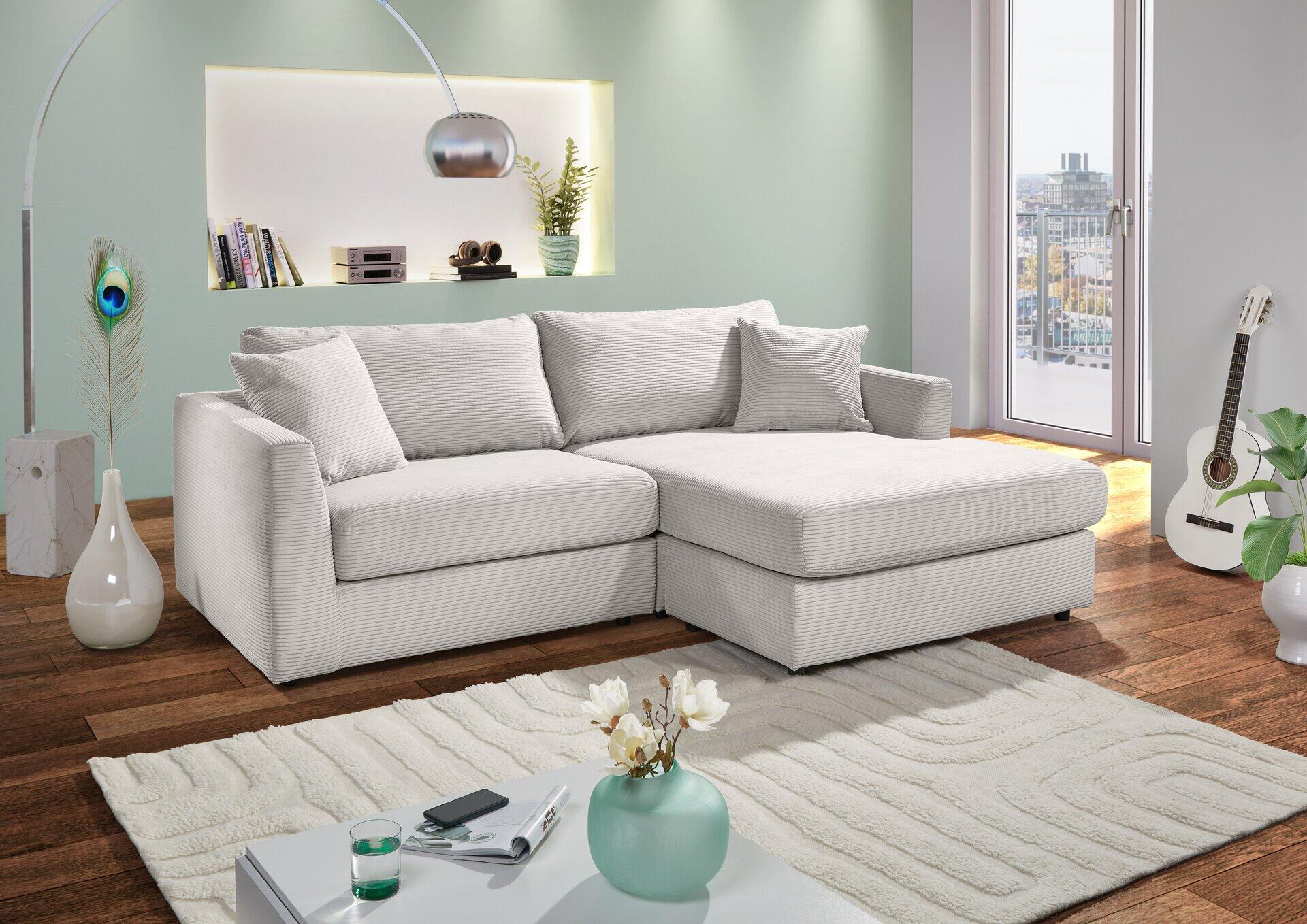 Eckcouch mit Chaiselongue in hellgrau, bestehend aus zwei separaten Elementen, die im rechten Winkel angeordnet sind.