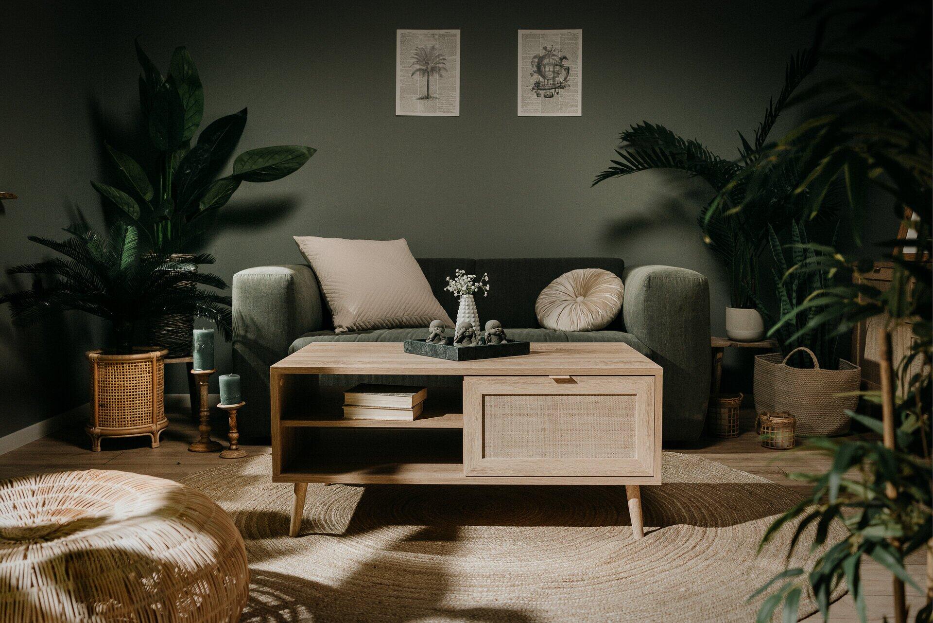 Couchtisch Bali 55A mit Schublade, Rattan-Gitterwerk und offenen Ablageflächen, präsentiert auf goldenen Füßen und im Fokus eines schrägen Lichteinfalles.