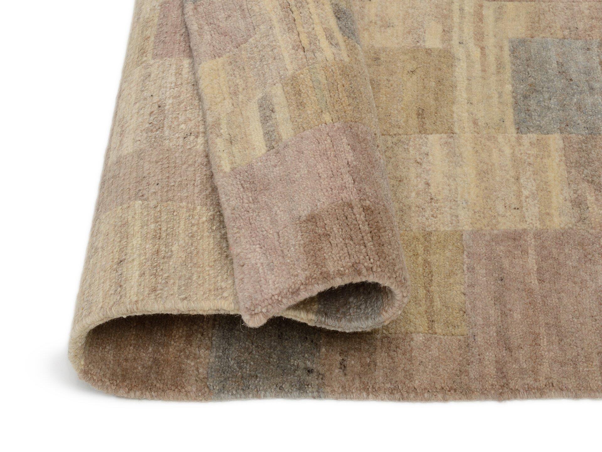 Nahaufnahme eines handknüpfte Teppichs aus Nepal, Badipur, mit flauschiger Textur, abstraktem Farbdesign in Beige, Grau, Braun und Rosa sowie sichtbarer Kante, die die Dicke des Teppichs betont.