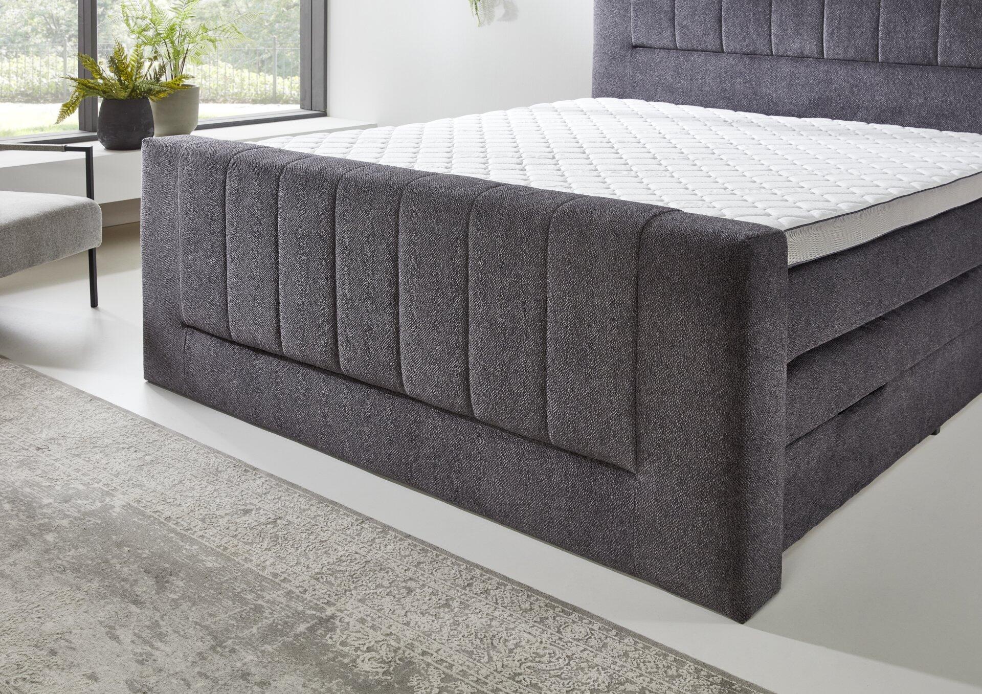 Graues Boxspringbett Kenosha BX2450 mit Quilted-Optik und niedrigem Bettrahmen aus der Seitenansicht.