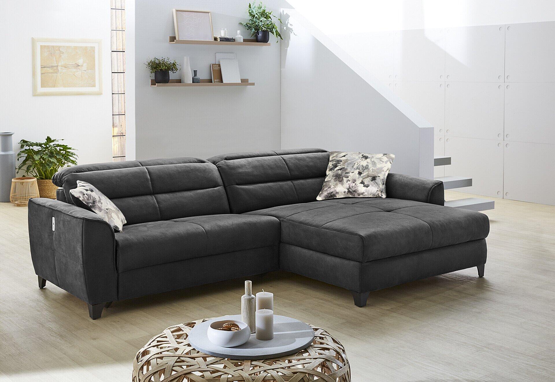 Wohnlandschaft Double One mit abgetretener Sitzfläche, Relaxfunktion und einem Kissen mit floralem Muster im modernen Wohnzimmer.
