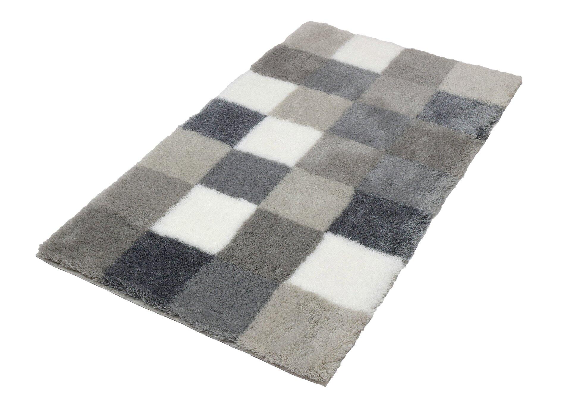 Badteppich Caro: Quadratischer Flanell-Badteppich mit Schachbrettmuster in Hellgrau und Dunkelgrau, aus erhöhter Perspektive aufgenommen, zeigt die flauschige Textur und einladende Atmosphäre.