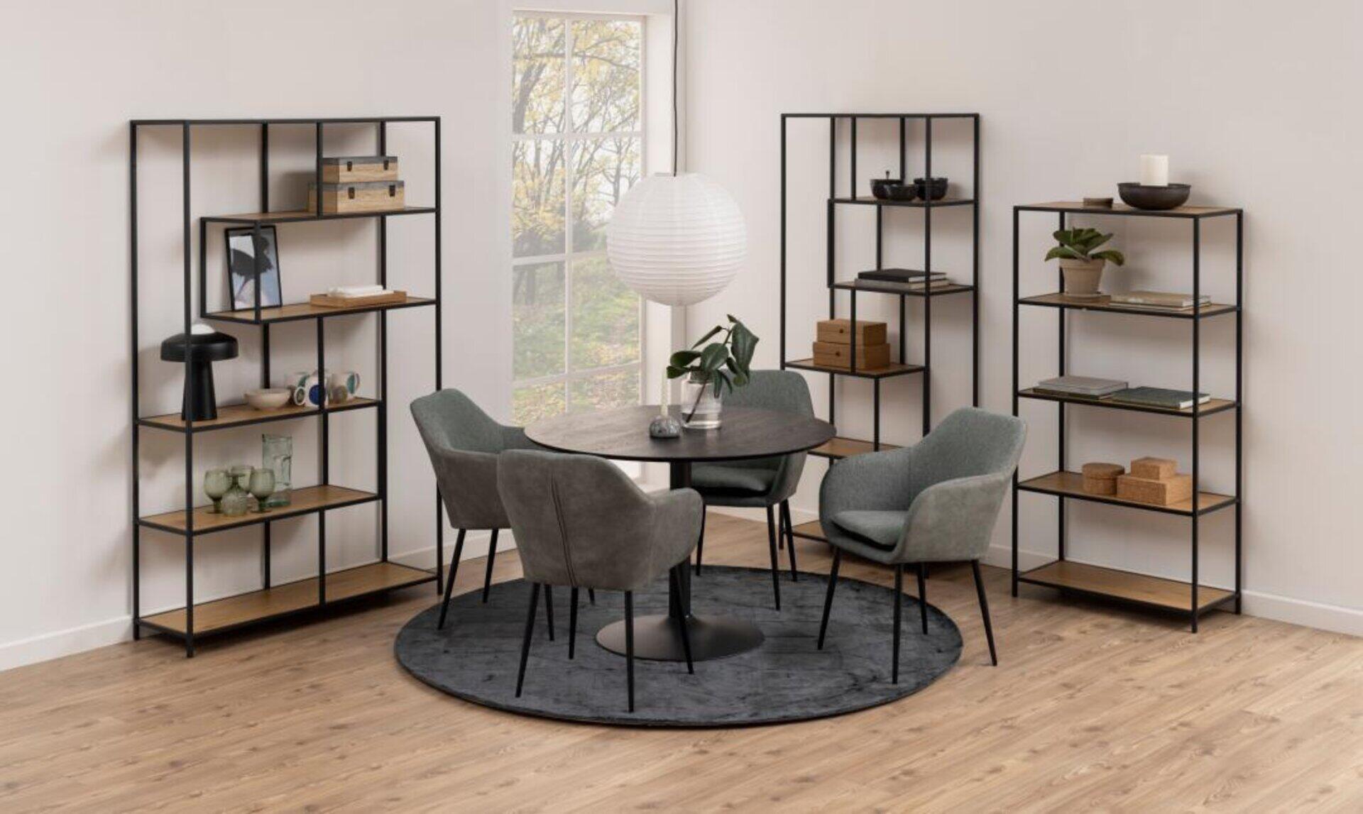 Hohes, schwarzes Regal Seaford mit Holzelementen und zahlreichen Ablageflächen für Bücher und Dekorationsgegenstände, eingebettet in eine stilvolle Sitzgruppe.