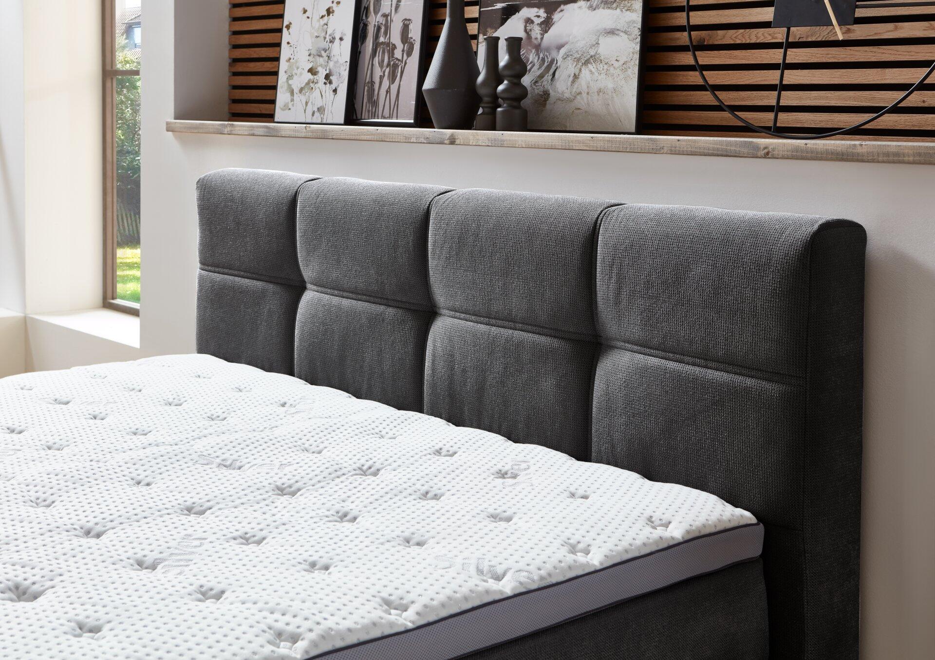 Detailaufnahme des Boxspringbettes Portage BX2110 mit grauem, gepolsterten Kopfteil und Memory-Schaum-Matratze.