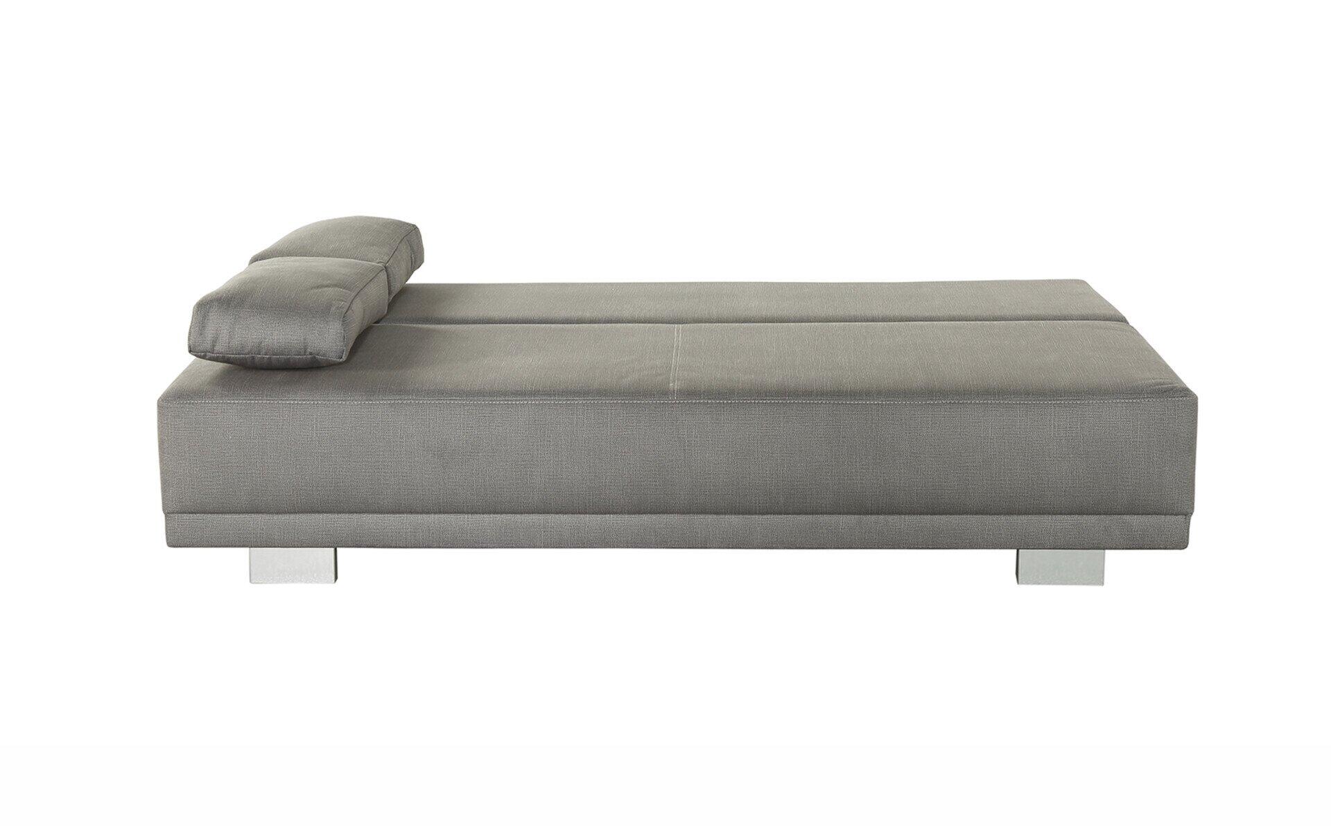 Schlafsofa Luzio in Grau mit silbernen Füßen, das im Bild aus Seitenansicht die moderne Form und das zusätzliche Kissen auf der rechten Seite zeigt.