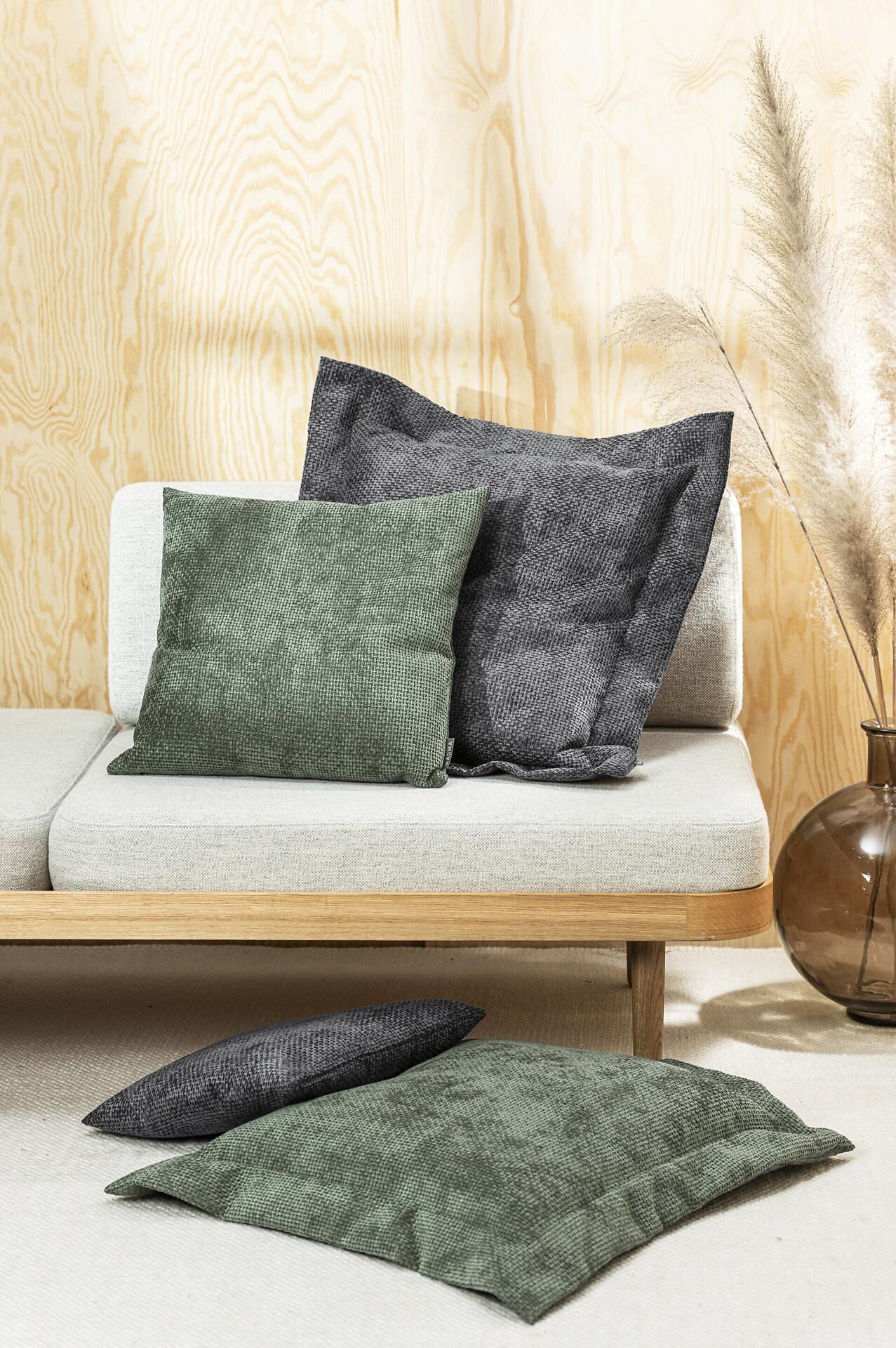 Flatterkissen Arlo in kupfernem Chenille mit Reißverschluss, arrangiert auf einem hellgrauen Sofa und auf dem Boden in einer gemütlichen Wohnsituation.