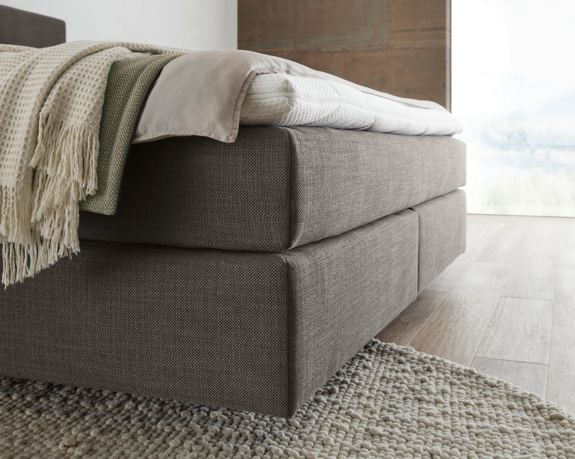 Boxspringbett Luxor Line BX mit TFK Boxspringunterfederung und grauem Stoffbezug, detaillierte Drahtperspektive zeigt die erhöhte Liegefläche und den massiven Eindruck des Bettes.