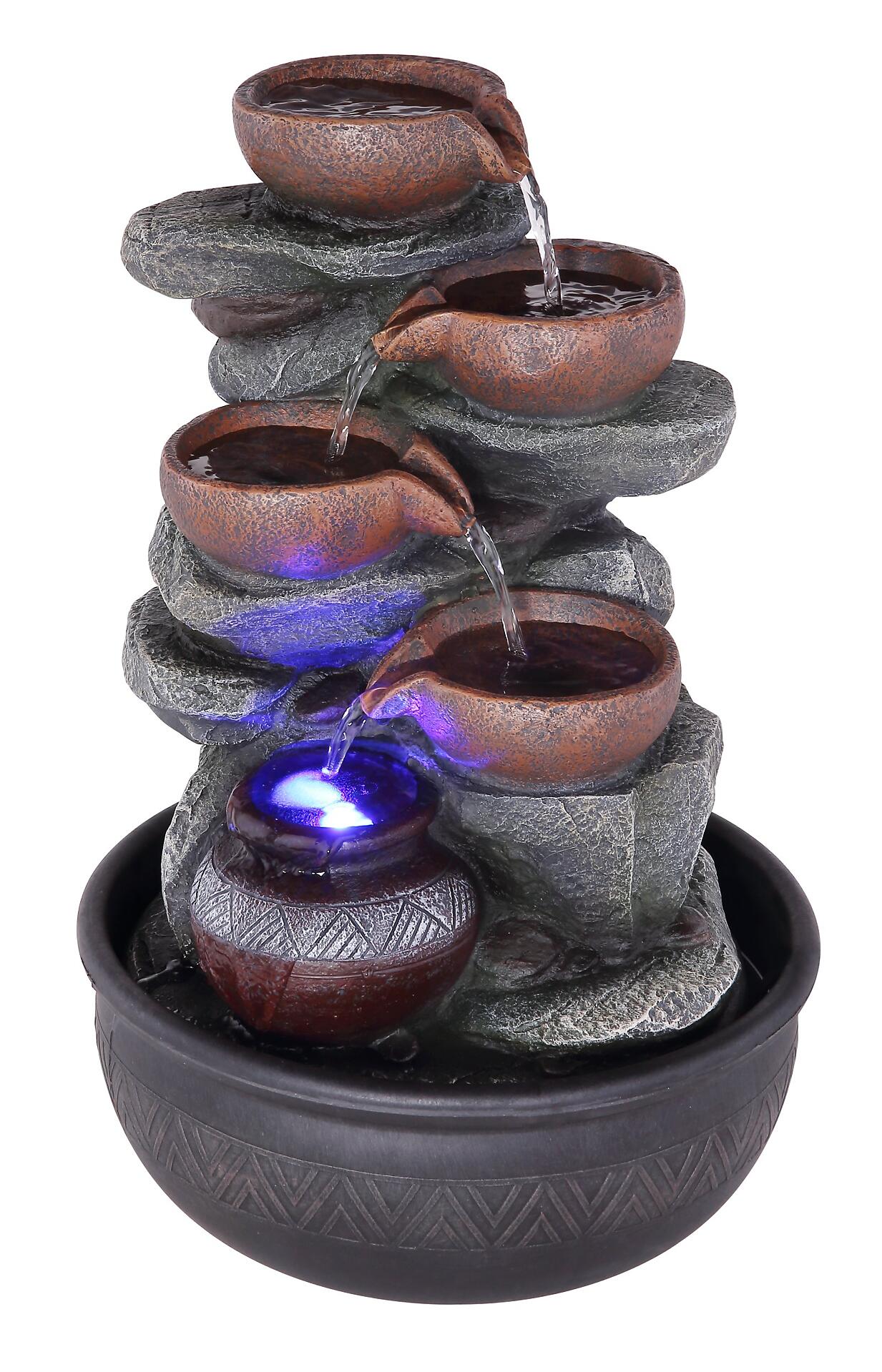 Brunnen FONTANA mit mehrstufiger Wasserfall-Konstruktion, tonfarbenen Becken und geometrischem Unterbau, beleuchtet von unten mit blauer LED.