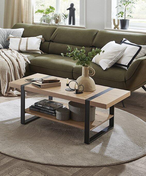 Couchtisch 25499 mit schwarzem Stahlrohrrahmen und hellem Eiche Dekor, schräg von vorne aufgenommen, zeigt die offene Ablagefläche und die Tischplatte mit Dekoration.
