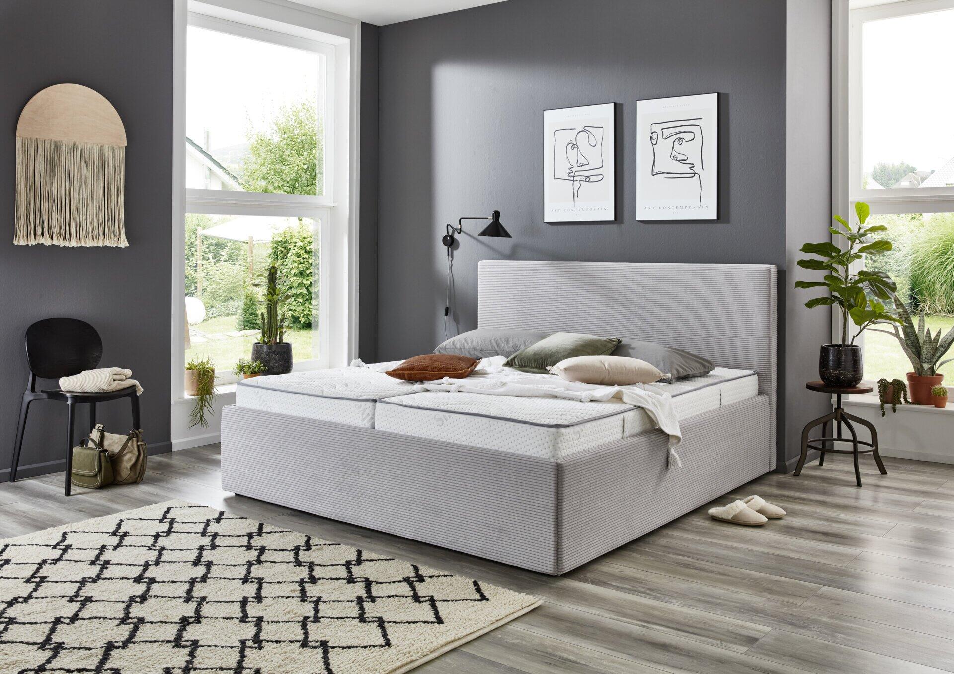 Polsterbett Calgary PB120 mit geöffnetem Bettrahmen und Stauraum unterhalb, Metallscharniere und helle Holzstütze sichtbar.