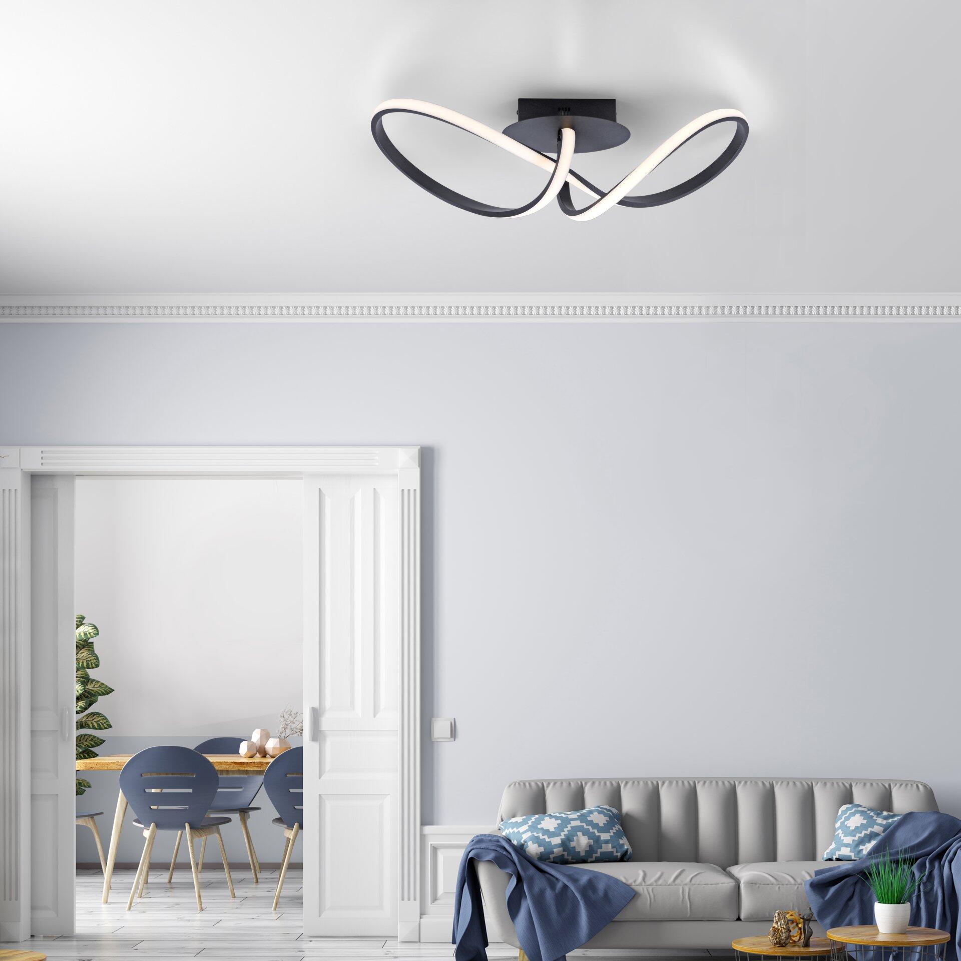 Deckenleuchte Maria mit gebogenem, weißem Design und schwarzem Gehäuse, die eine angenehme Beleuchtung in einem modernen Wohnzimmer erzeugt.