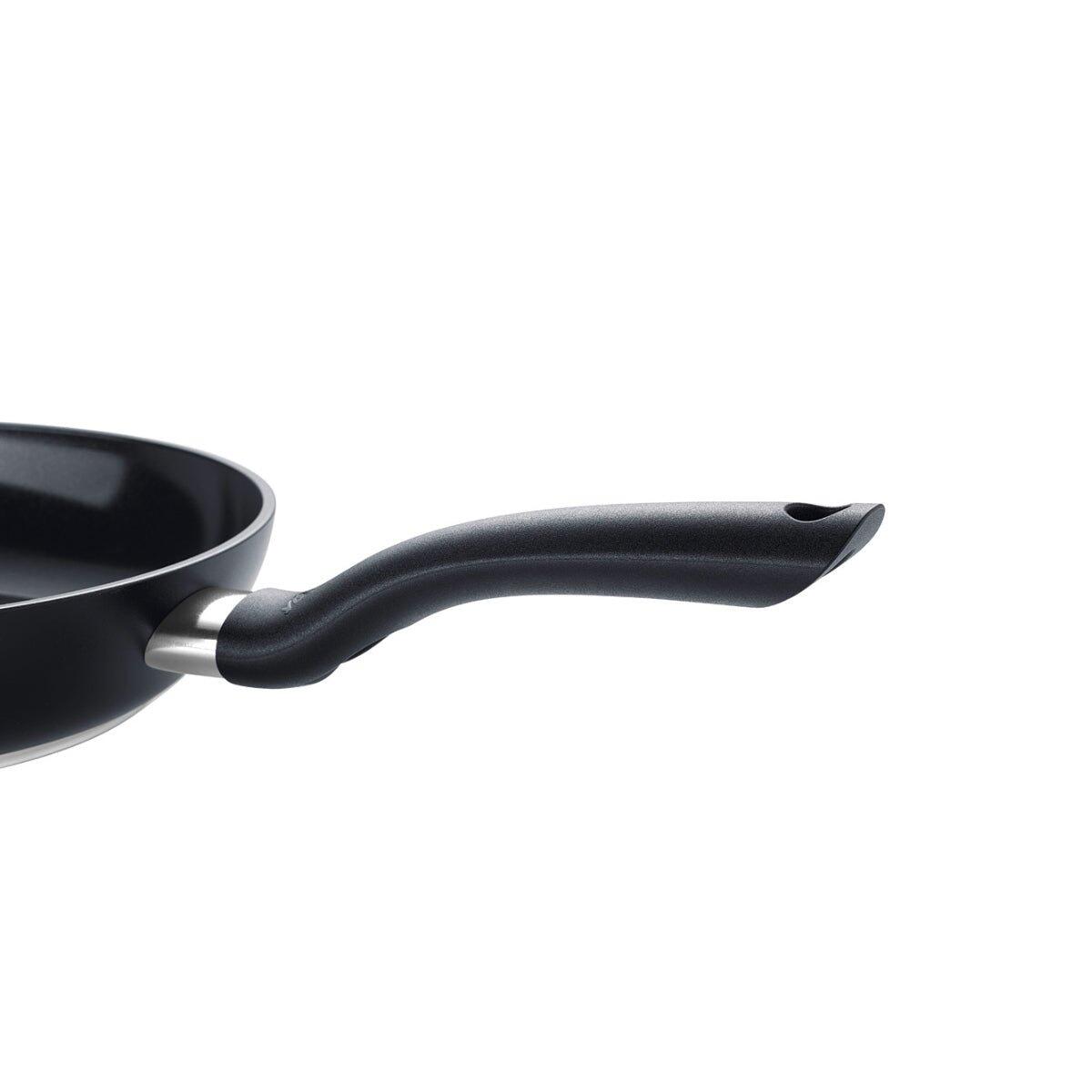 Detailaufnahme des ergonomisch geformten, schwarzen Kunststoffgriffs der Fissler Essential Pfanne mit Edelstahlrand, aus Seitenperspektive.