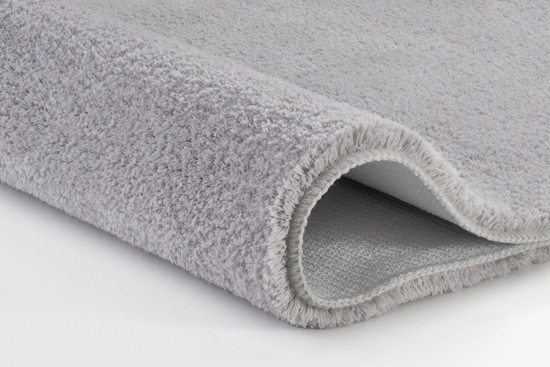 Badteppich Marco, silbergrau gerollt, Detailaufnahme der flauschigen Textur und der strukturierten Rückseite.