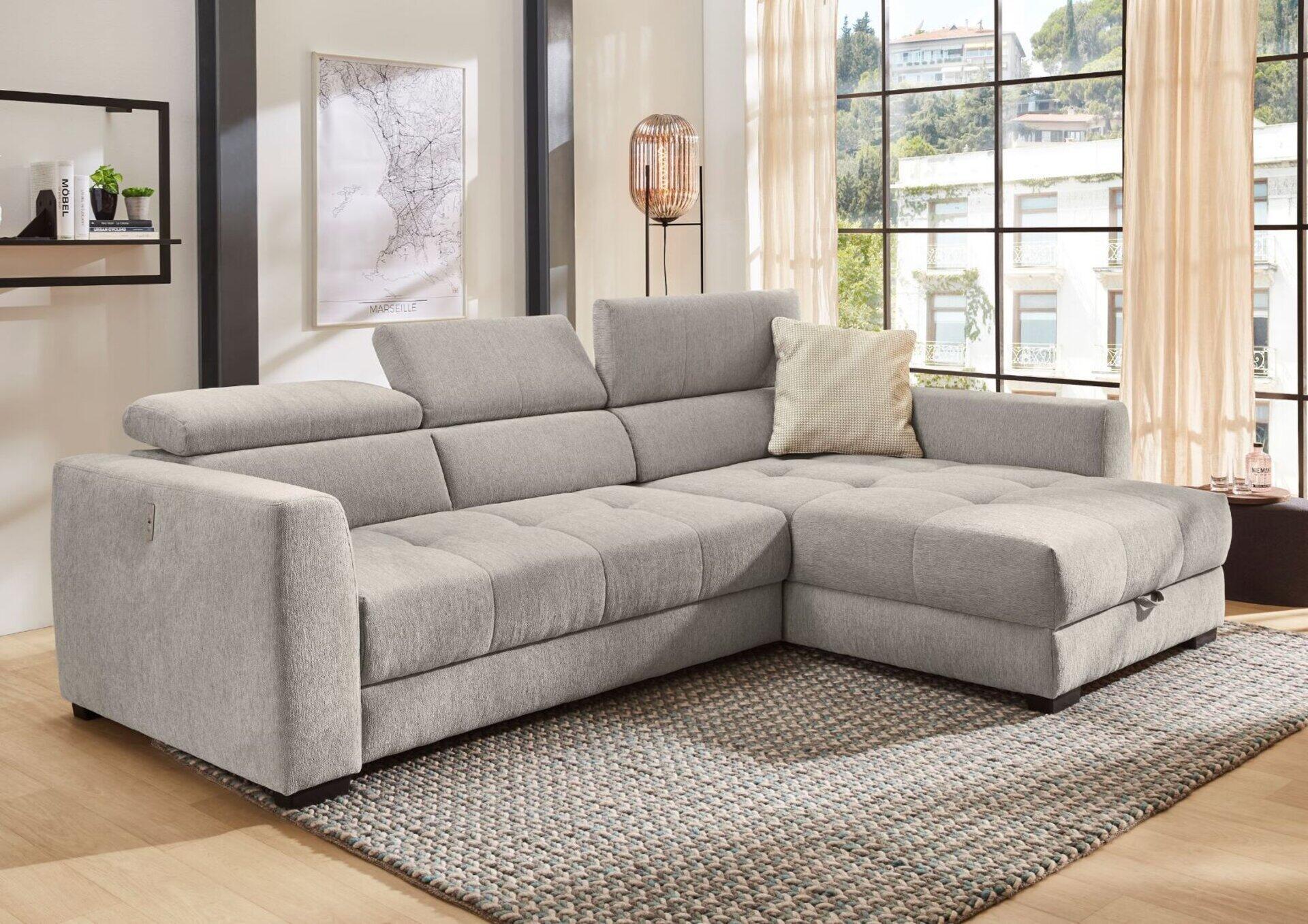 Graue Wohnlandschaft San Marino mit Bettkasten und hochgeklapptem Schlafsofa, aus leicht erhöhter Frontalperspektive in einem modernen Wohnzimmer.