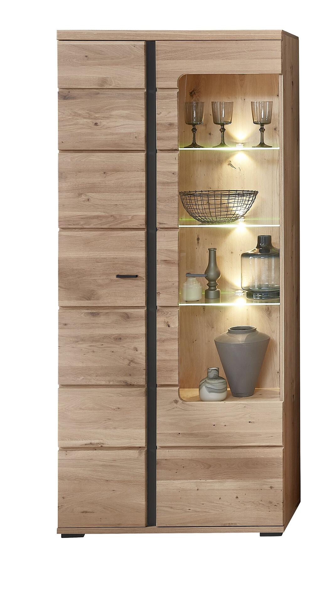 Vitrine Sonos II mit gebürsteten Eichenholztüren und Glastür, beleuchteter Innenraum mit Dekorationsgegenständen und schwarzem Sockel.