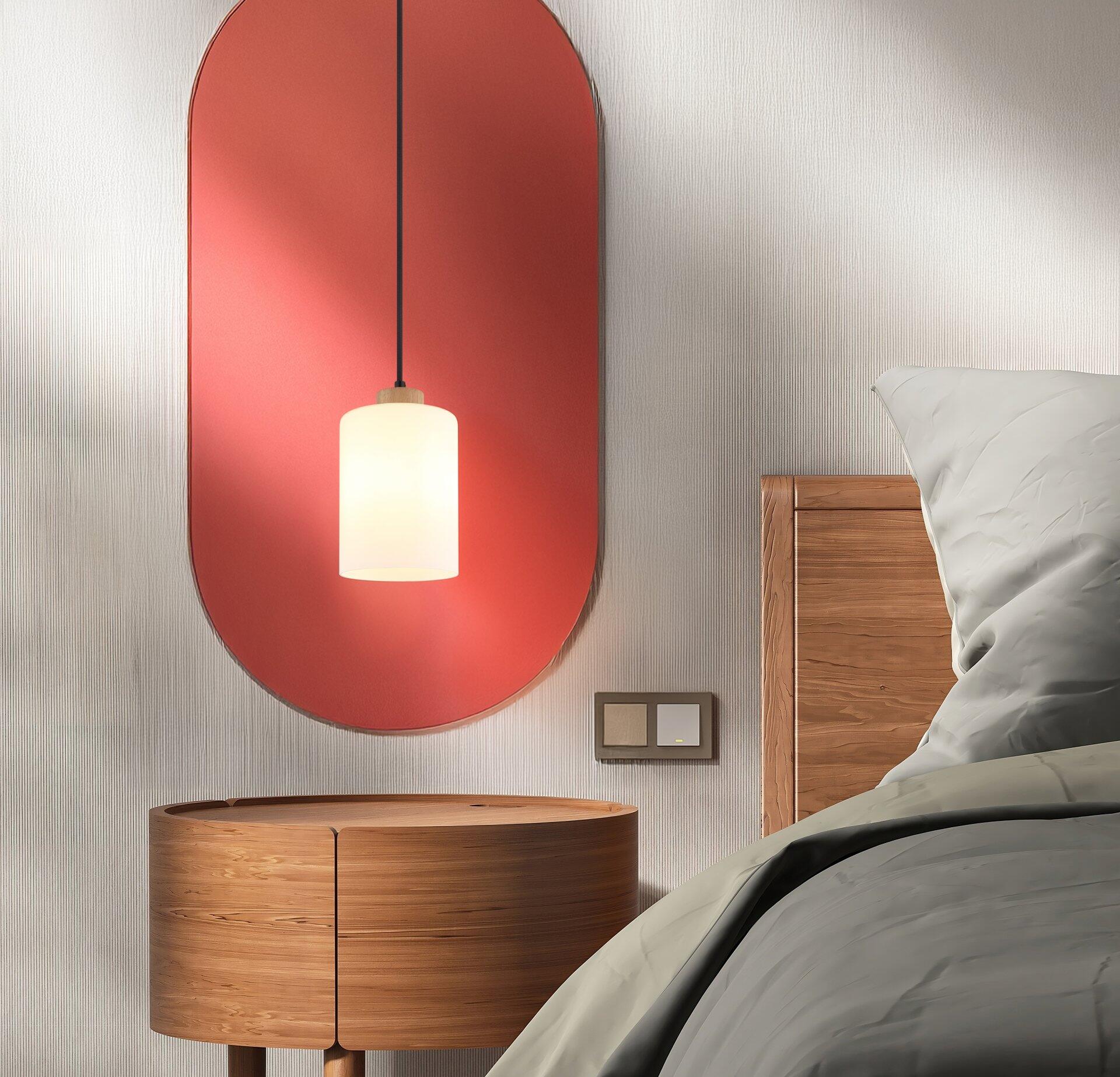 Wandlampe ROWENA mit ovalem Lampenschirm, befestigt an einem dünnen Stiel, integriert in ein stilvolles Schlafzimmer mit rundem Nachttisch und Steckdosenanschluss.